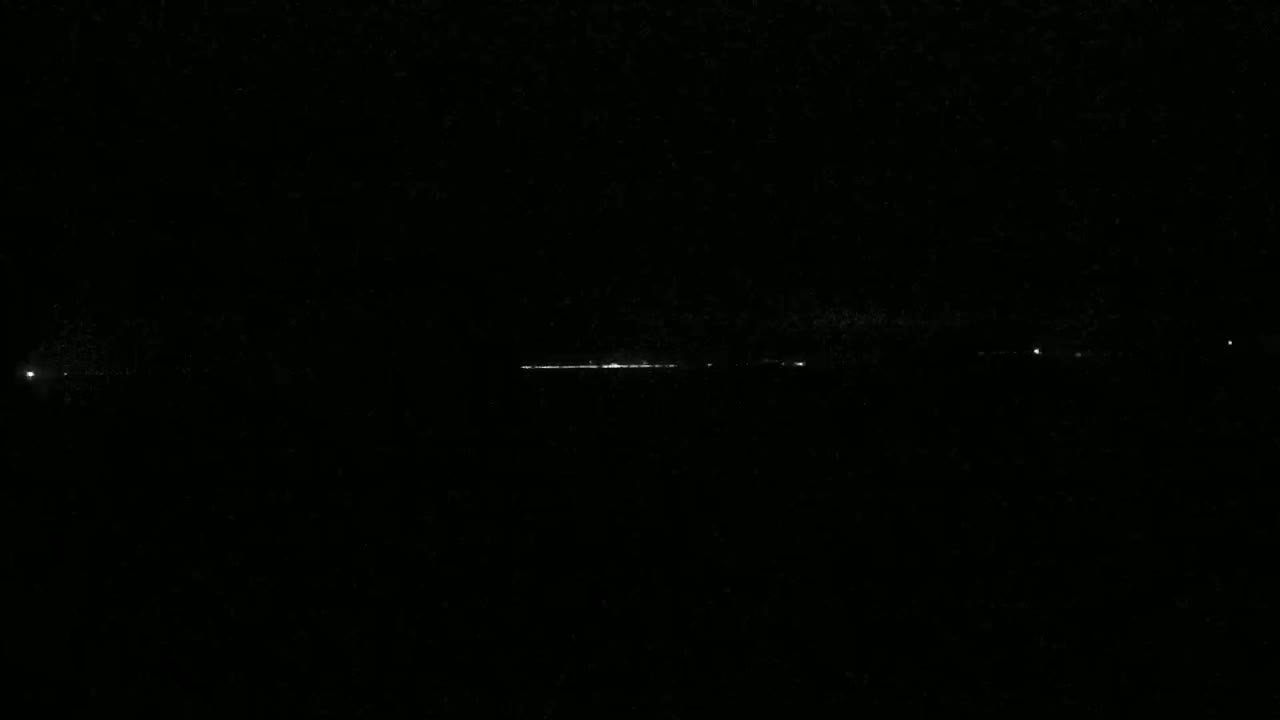 A long, faint line of distant lights is visible on a dark, nighttime horizon.