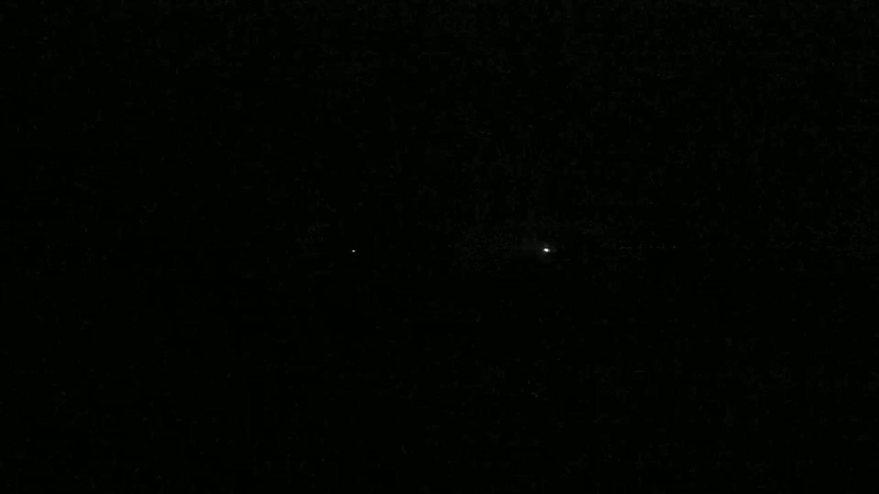 Two bright points of light are visible in a dark, night sky.