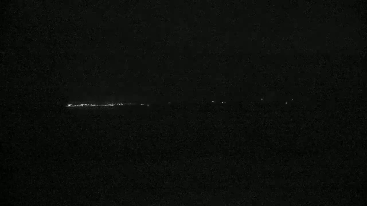 A long, thin line of lights is visible on the horizon at night.