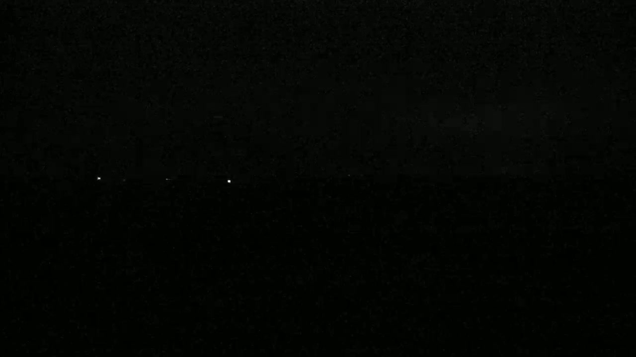 A dark, nighttime scene shows a few distant lights on the horizon.