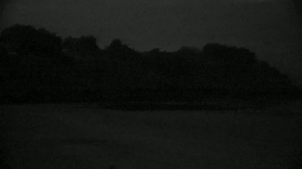A dark, indistinct shoreline is barely visible under a very dark, overcast sky.