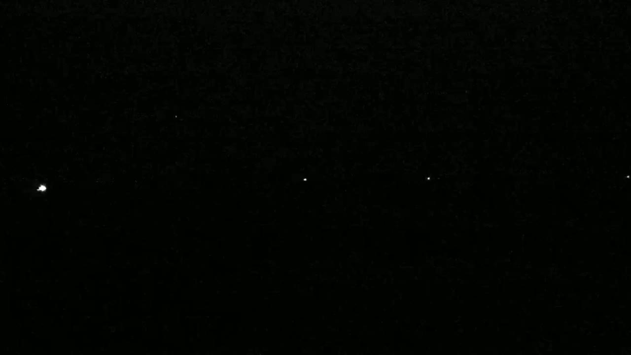 A dark night sky shows five bright points of light aligned horizontally.