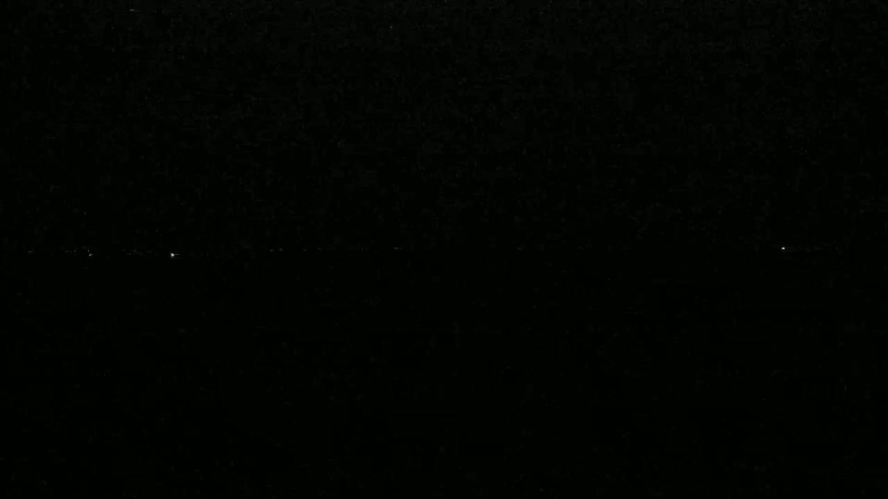 A nearly black image shows a faint horizontal line of very small, sparse, white lights.