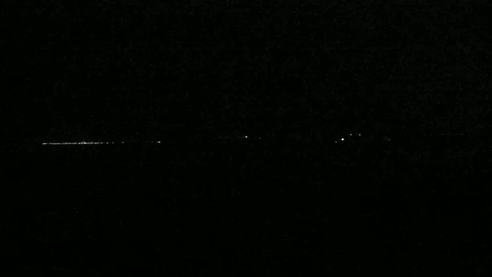 A long, thin line of faint white lights appears on a dark, possibly nighttime, background.