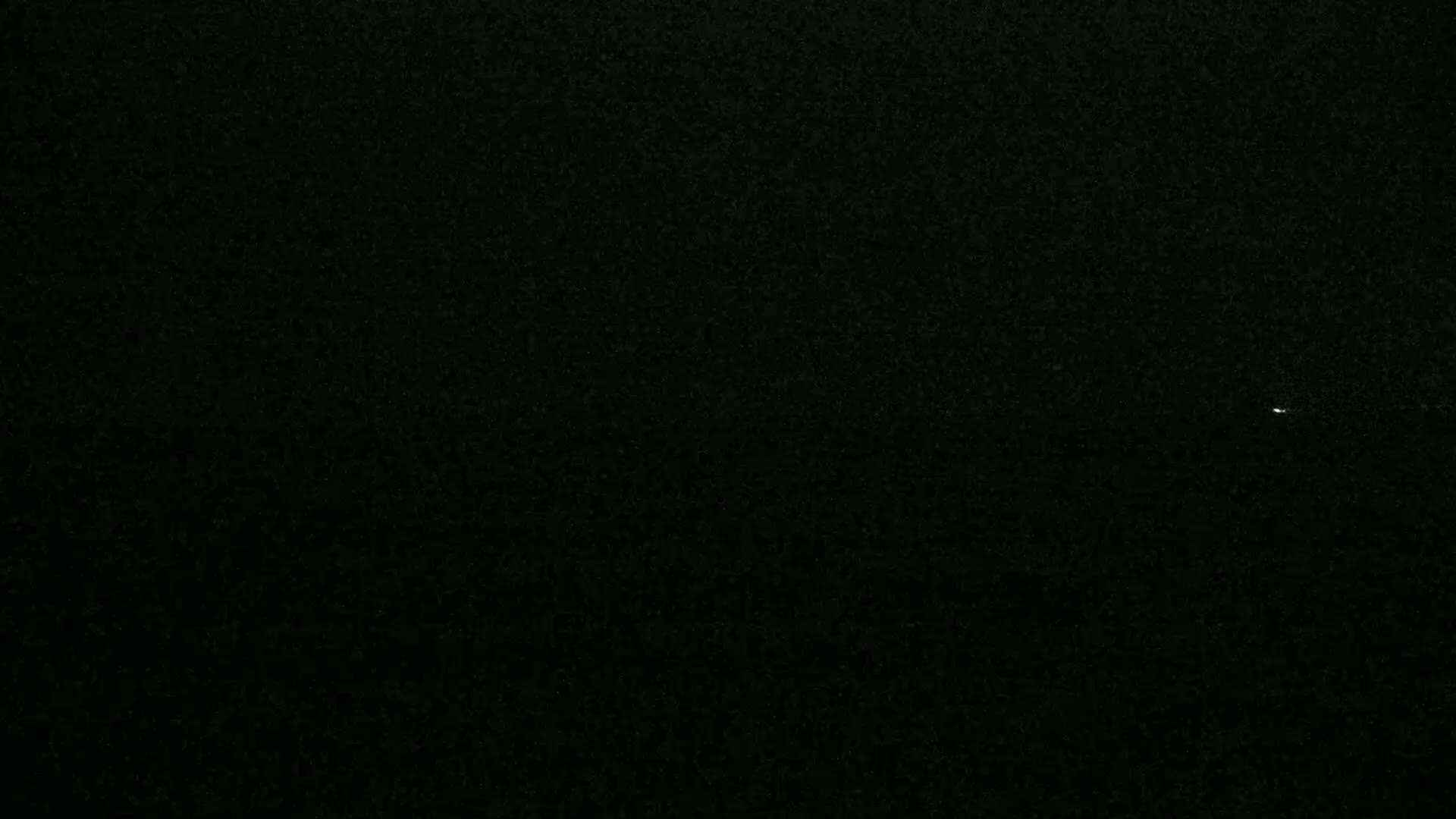 A tiny, faint light is visible in a dark, night sky.