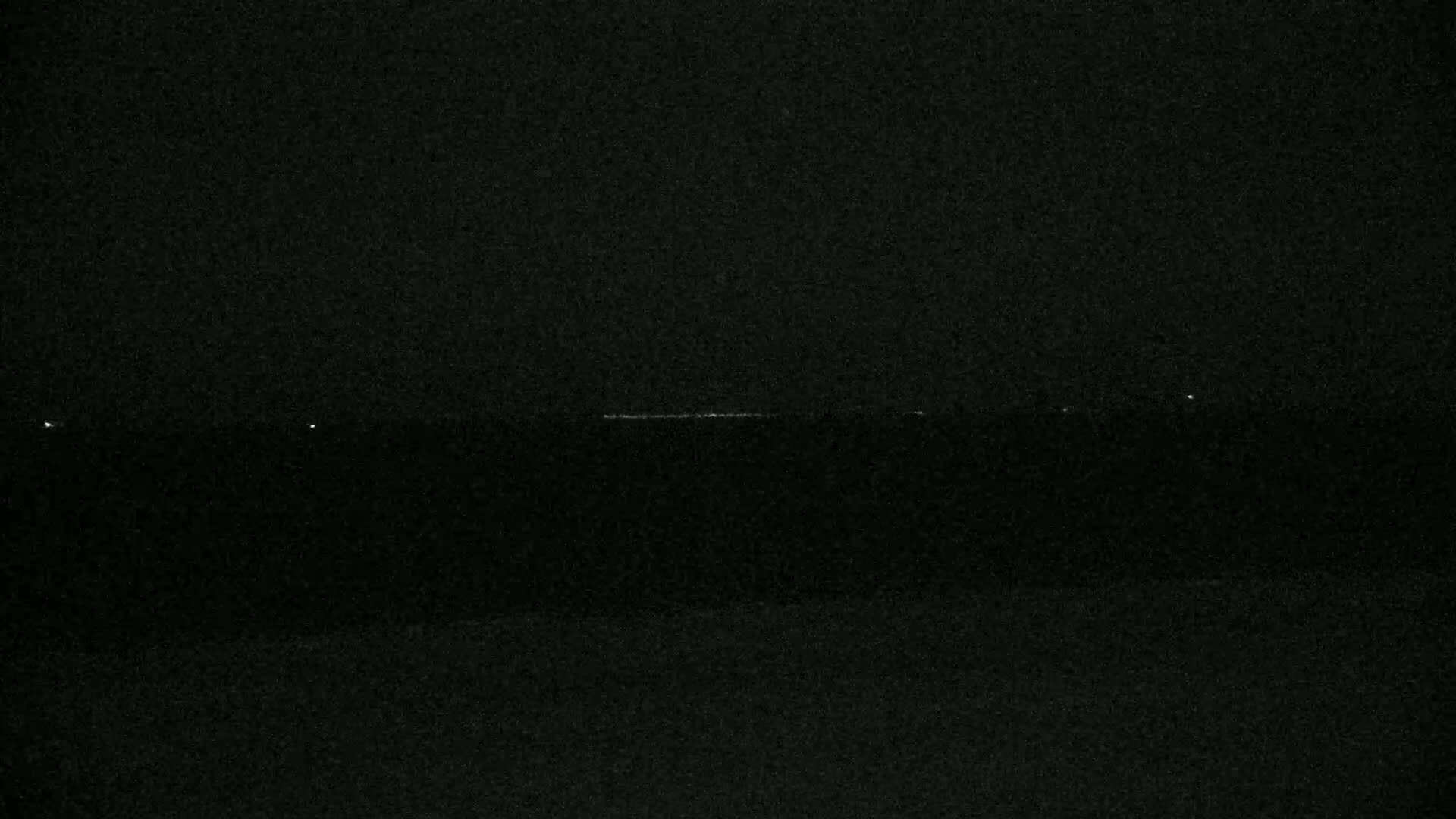 A faint, horizontal line of light is visible in the distance against a dark, nighttime sky.