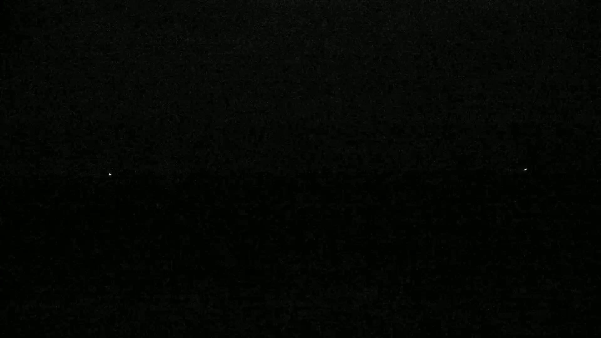 A mostly black image shows two faint, small points of light against a dark background.