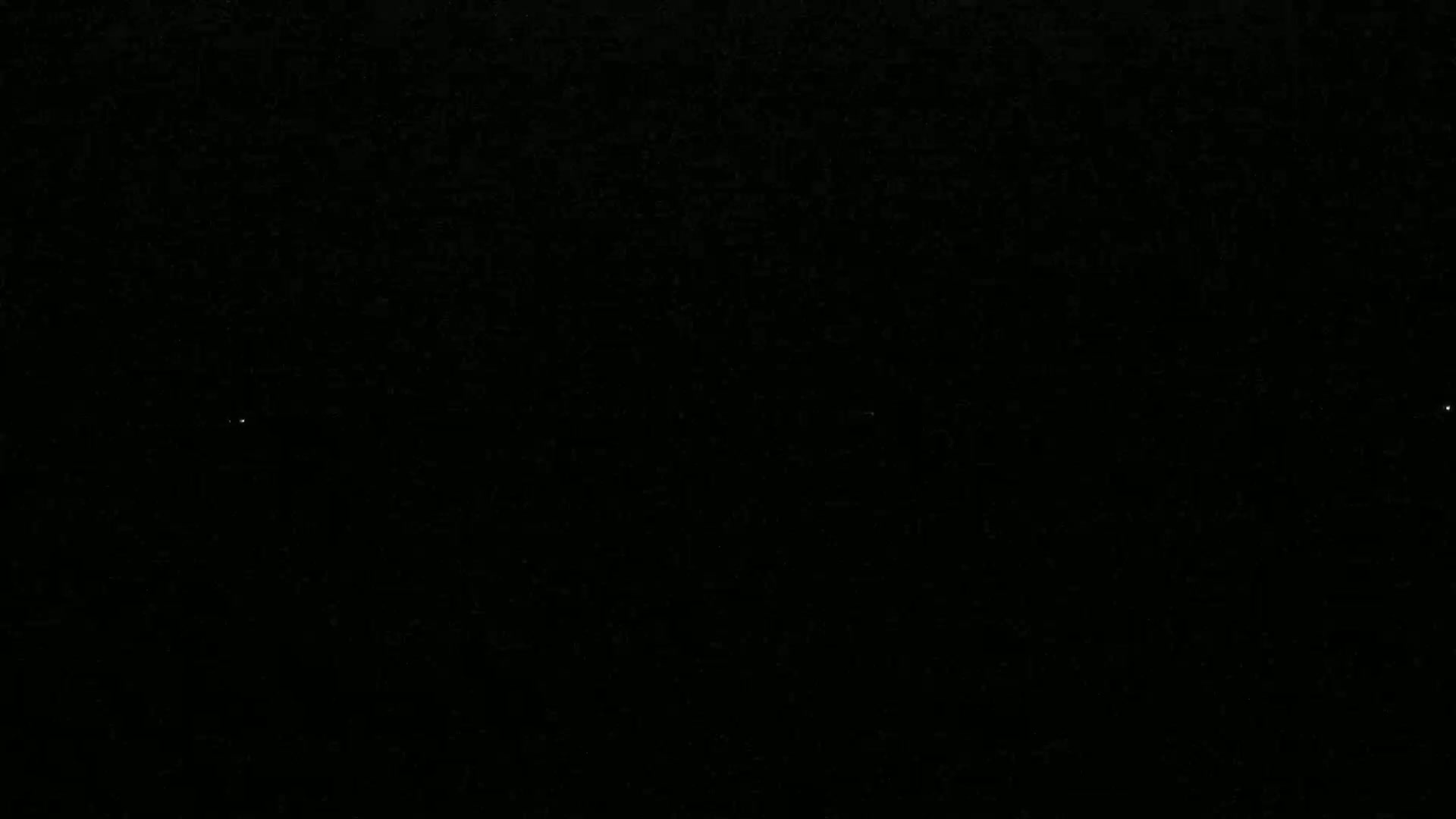 A mostly black image shows three faint points of light against a dark night sky.