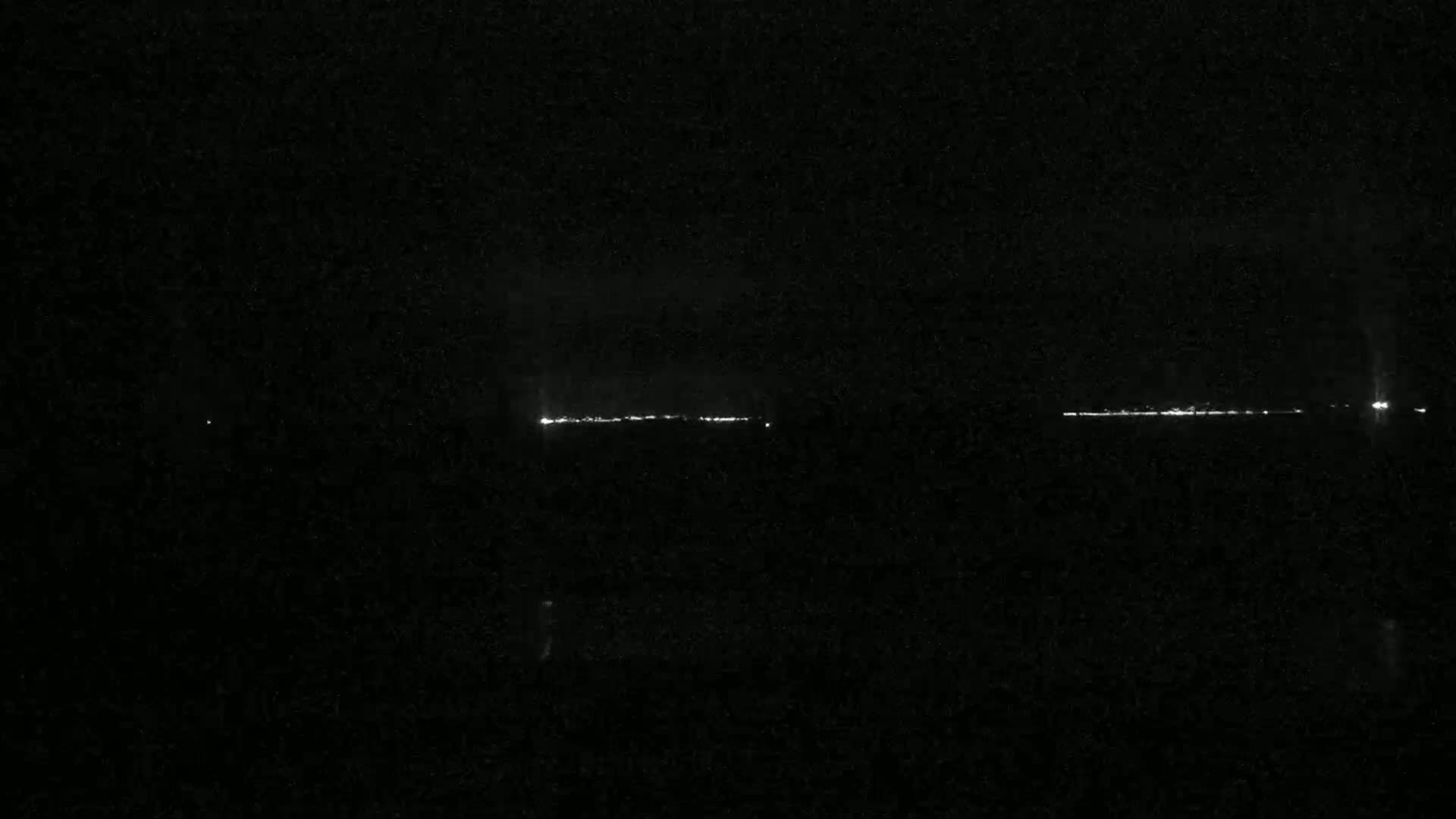 A long line of distant lights is visible on a dark, nighttime horizon.