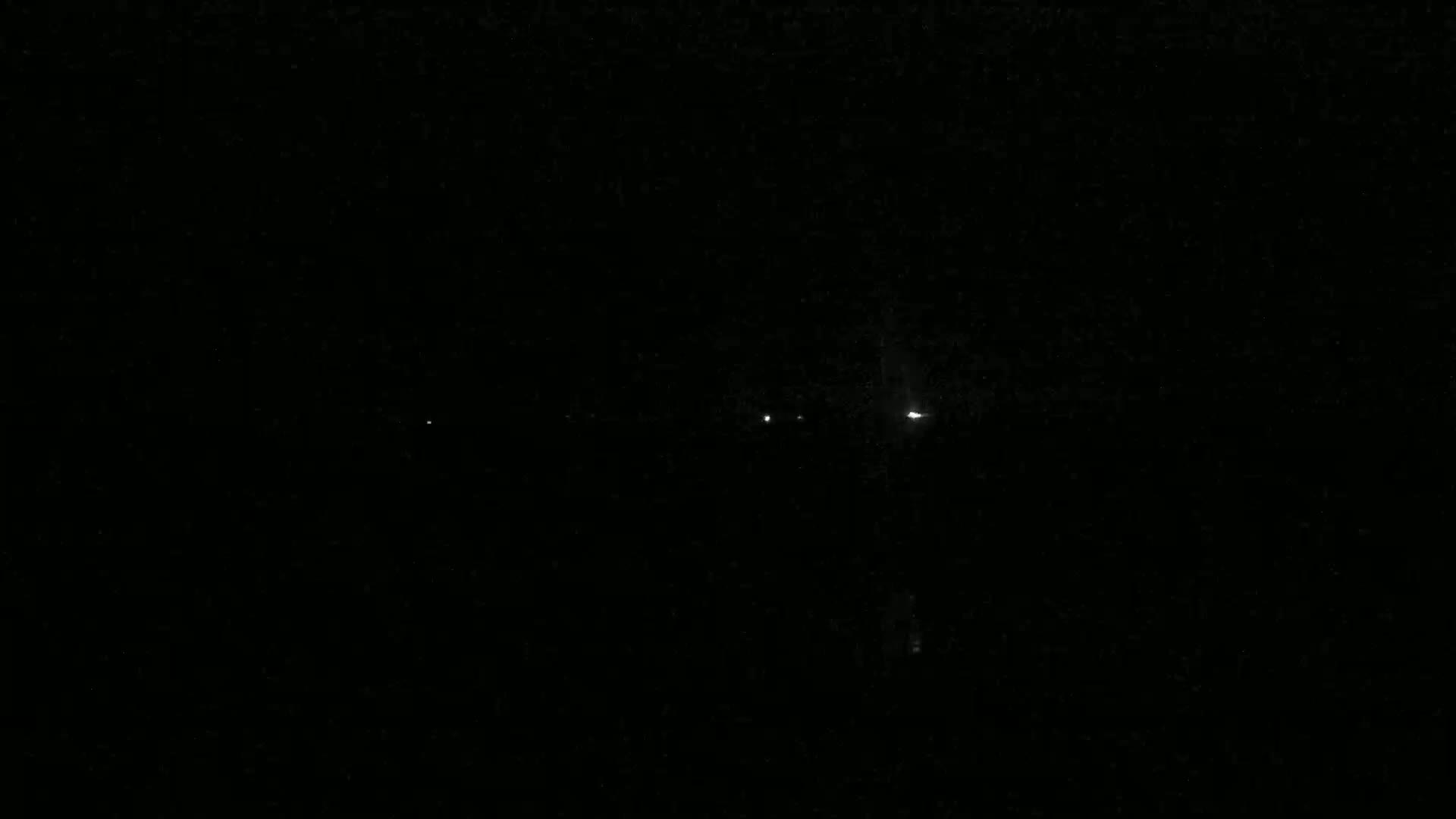 A dark, nighttime scene shows several faint, distant lights.