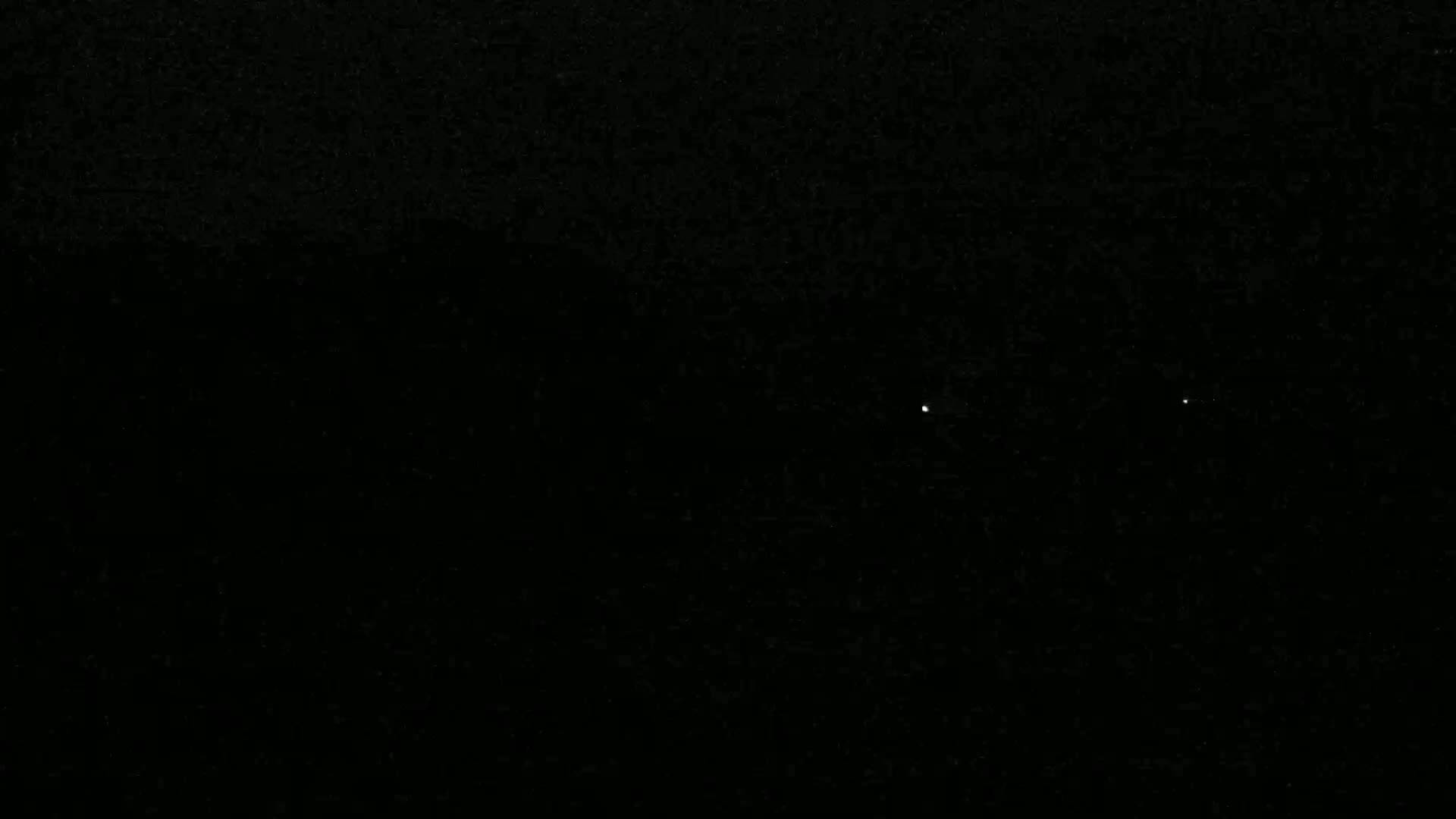 A nighttime image shows a dark sky with three faint, distant lights.