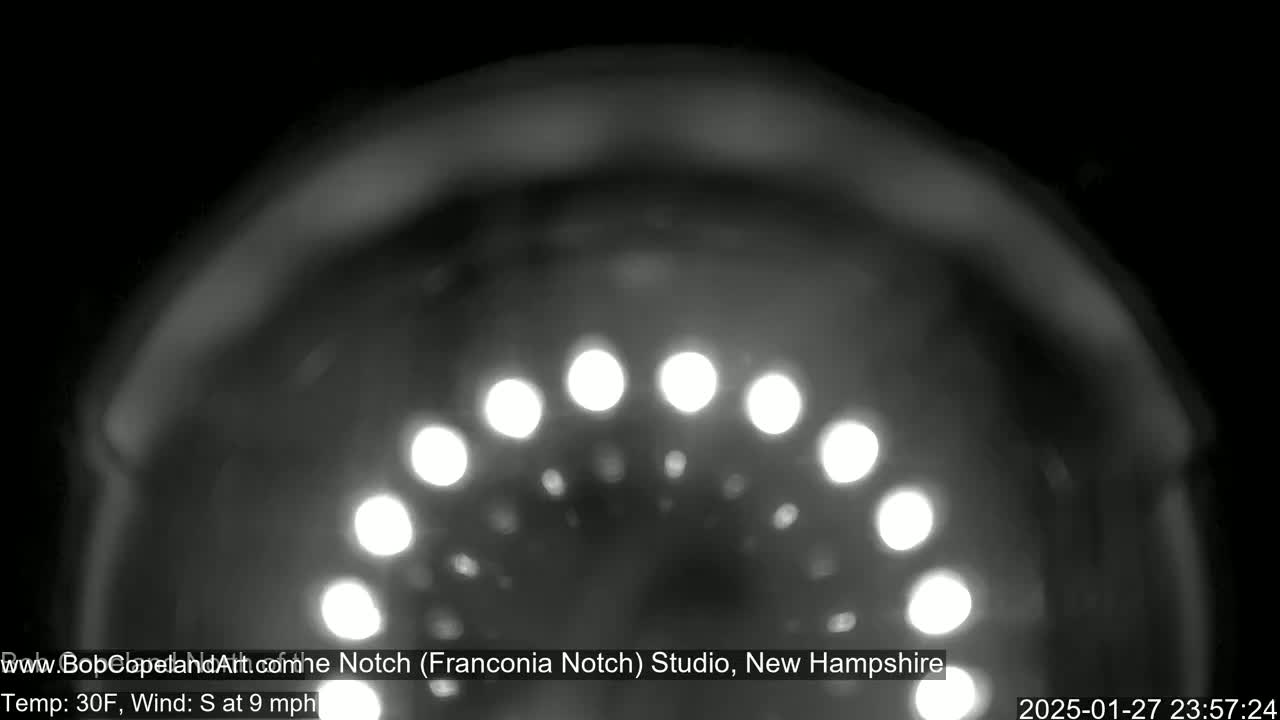 A blurry, nighttime image shows a semicircle of bright lights against a dark, possibly snowy background.
