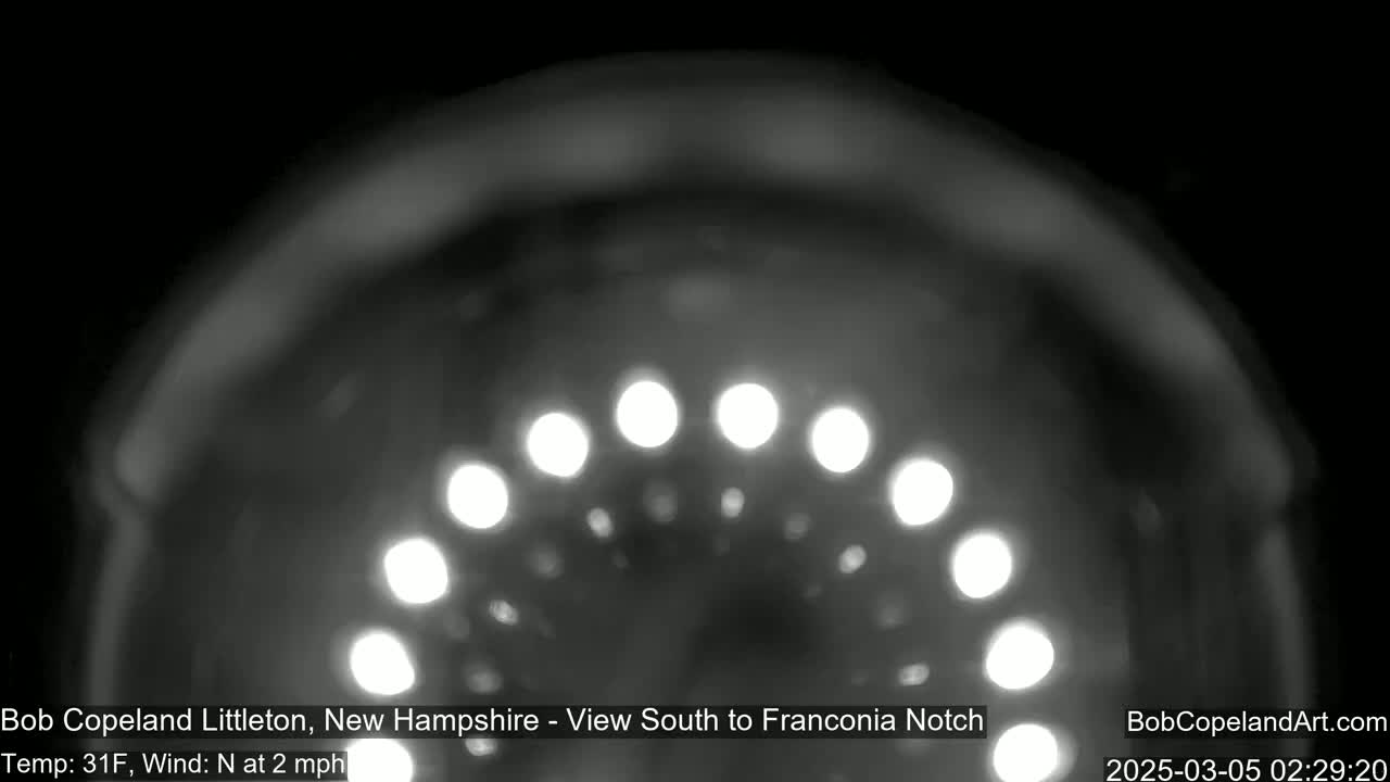 A nighttime, blurry view of a semi-circular arrangement of lights, with a temperature of 31 degrees Fahrenheit and a north wind at 2 mph.