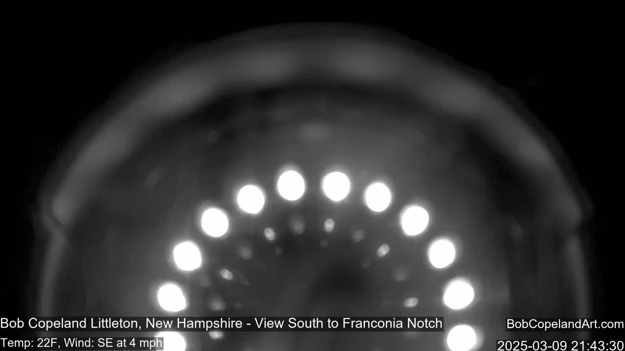 A blurry, nighttime image shows a semi-circular arrangement of out-of-focus lights against a dark background, with a 22°F temperature and a southeasterly wind at 4 mph.
