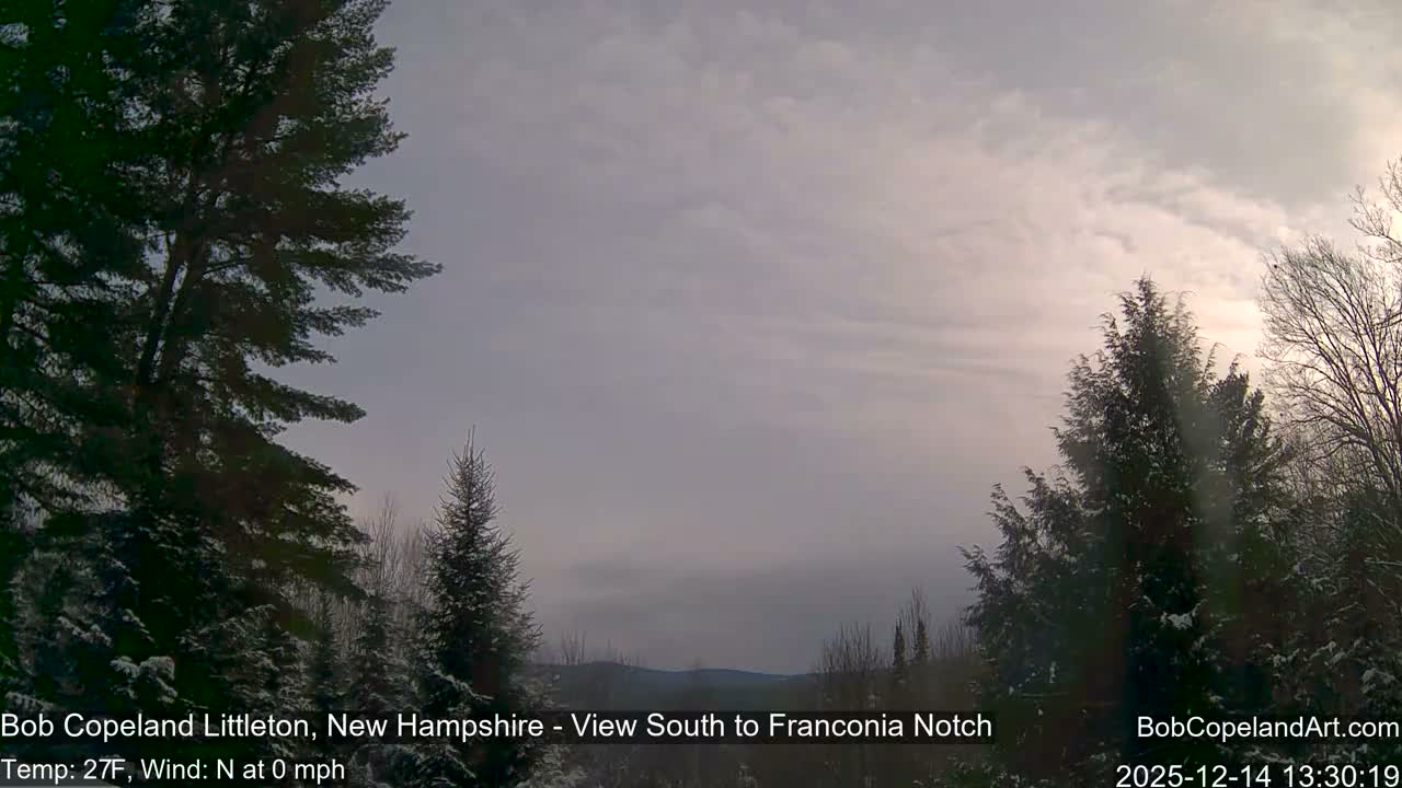 A blurry, monochromatic nighttime outdoor scene displays an arc of bright, circular lights through what appears to be a camera dome, with a temperature of 21F and no wind.