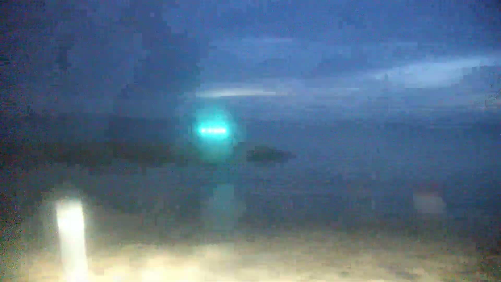 A blurry, nighttime image shows a dark body of water under a dusky sky, with a faint light visible in the distance.
