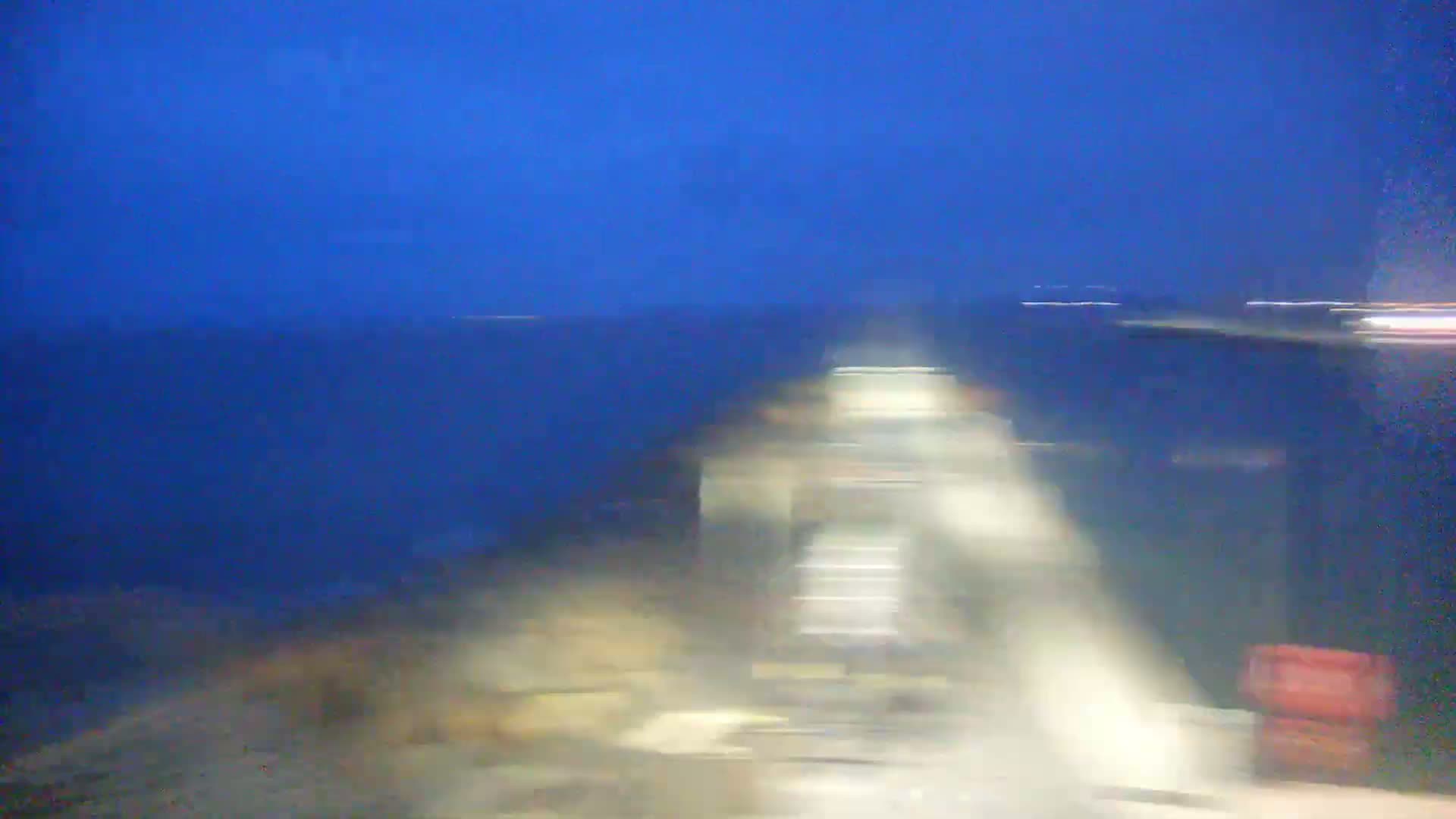 A blurry image shows a nighttime view of an indistinct landscape under a dark blue sky.