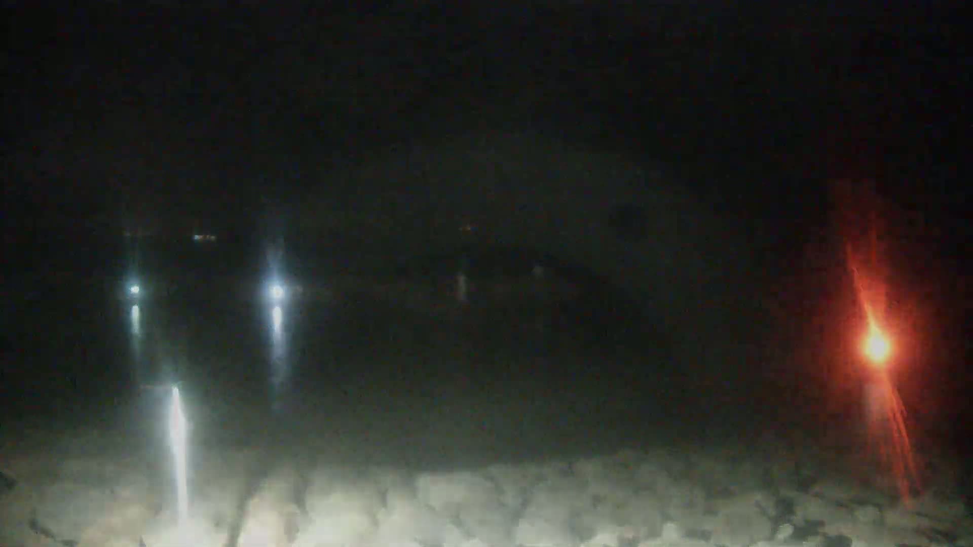 At night, several figures with bright lights are visible on a rocky surface, and a red flare burns in the distance.