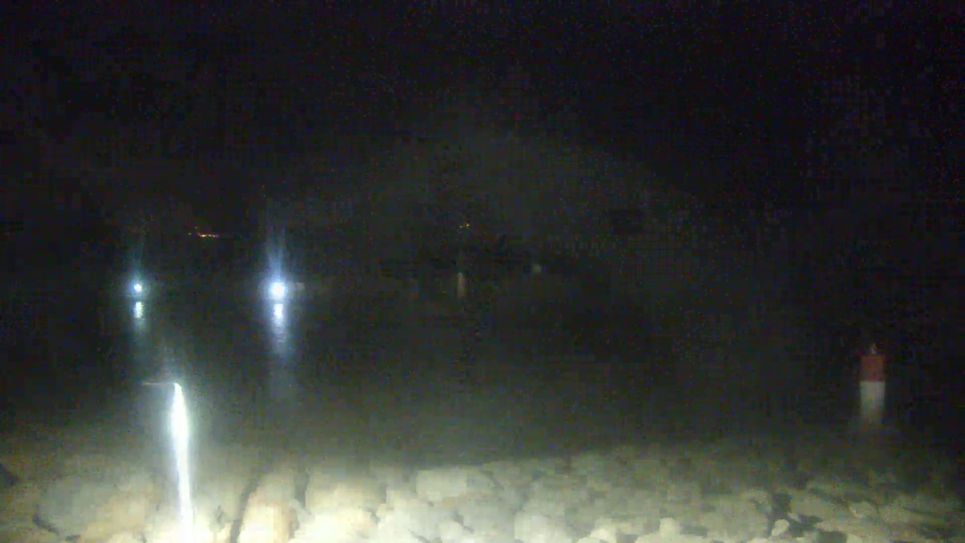 Two sets of headlights are visible on a dark, rocky surface at night.
