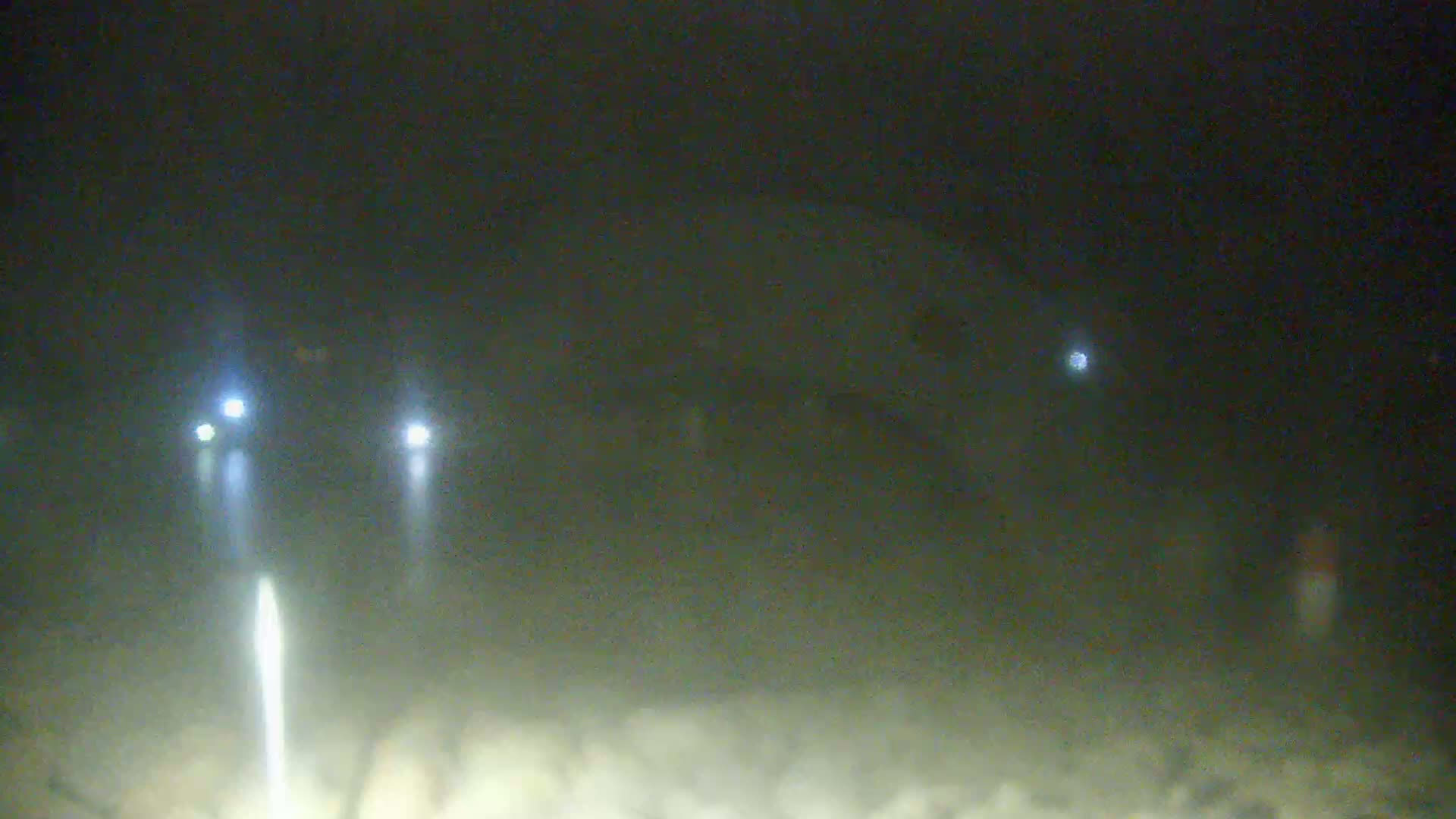 Headlights from two vehicles are visible on a foggy, dark night.