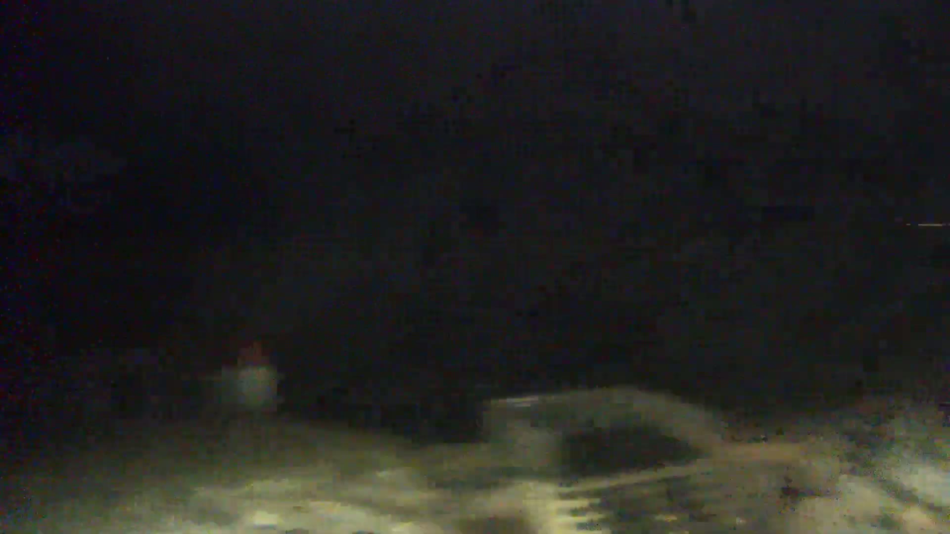 A blurry, dark image shows what appears to be a nighttime, outdoor scene with indistinct shapes suggesting vehicles or objects on the ground.