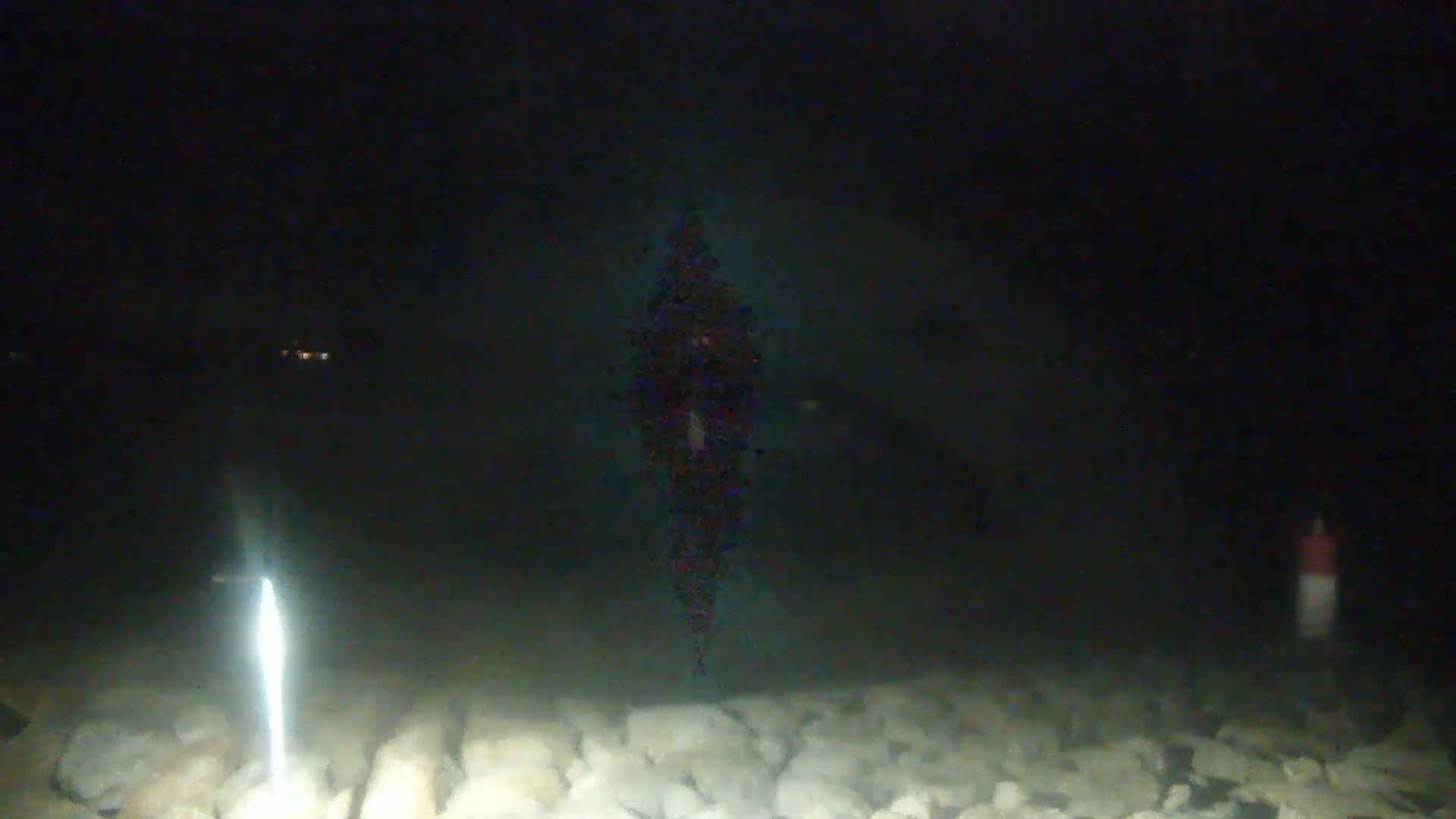A blurry, dark image shows a bright light illuminating a rocky surface at night.