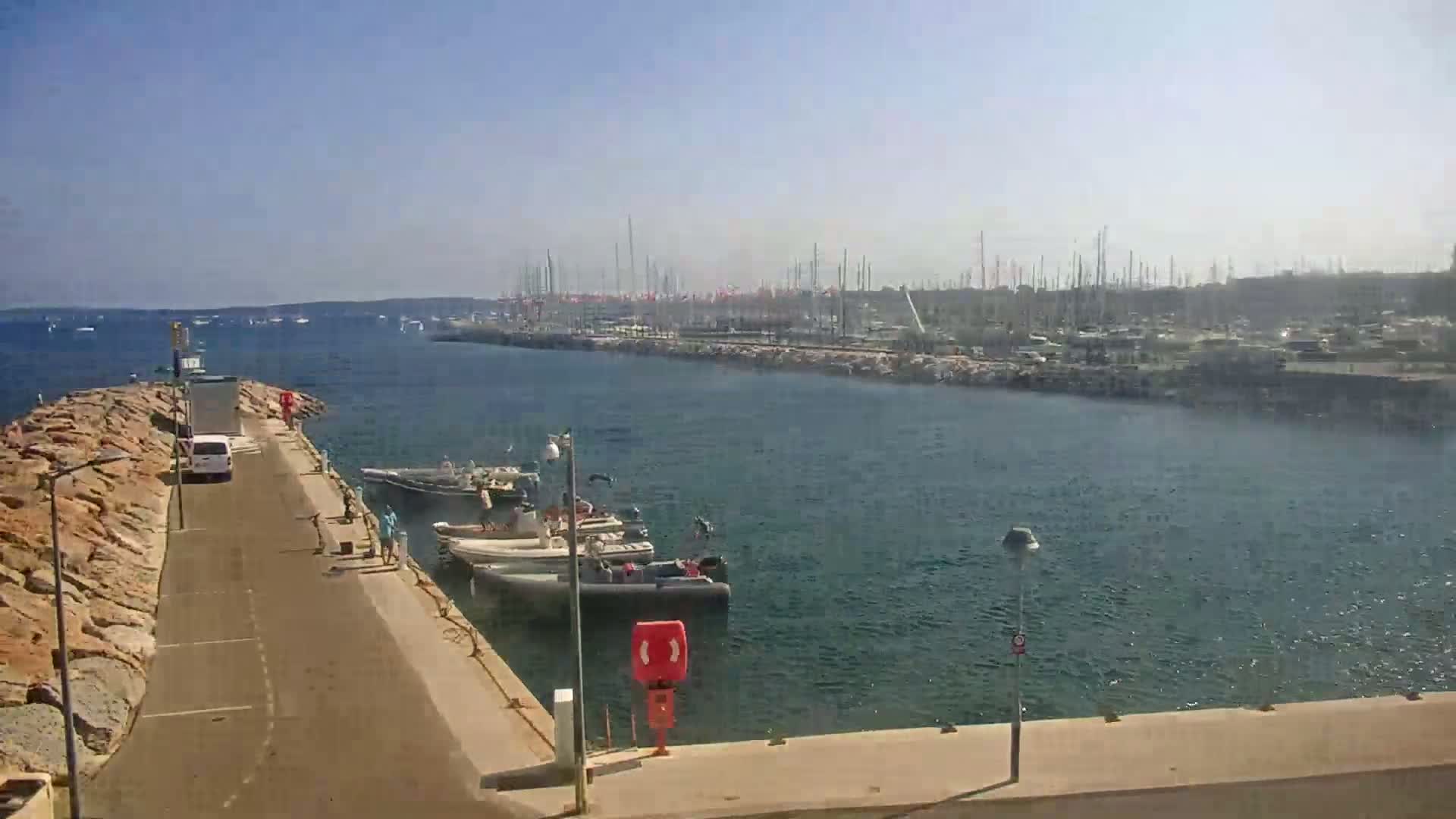 A harbor filled with numerous boats and yachts under a clear, sunny sky.