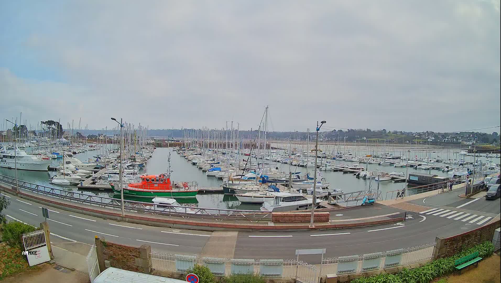 A marina filled with numerous sailboats and motorboats under a cloudy sky.