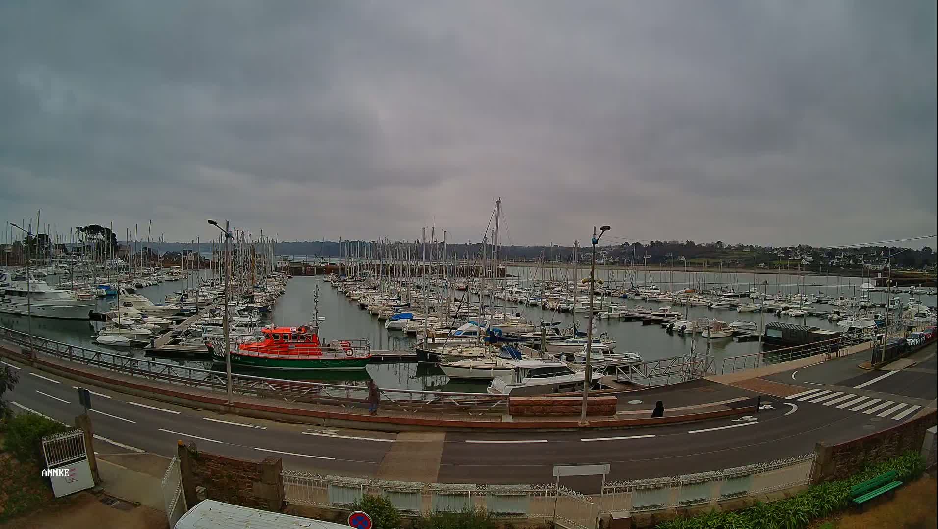 A marina filled with numerous sailboats and motorboats is seen on an overcast day.