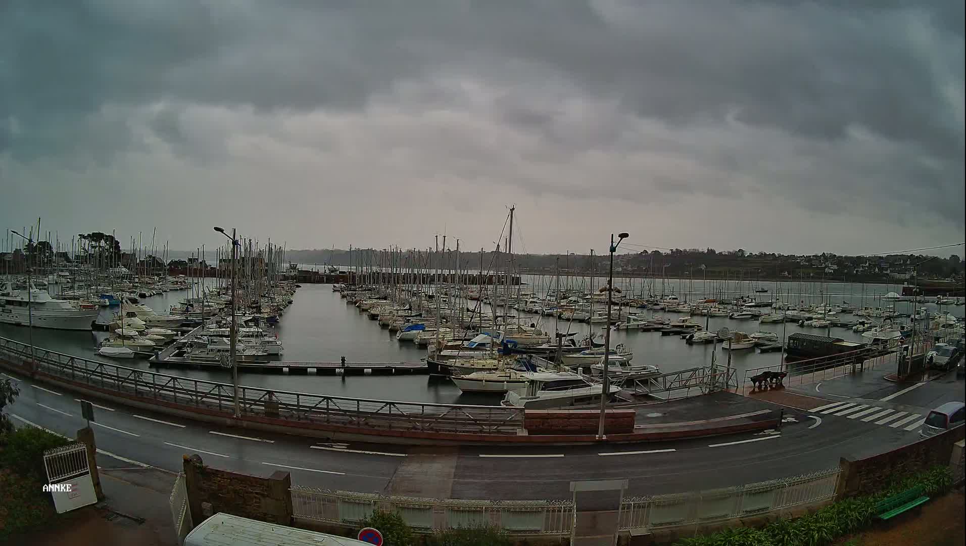 A marina filled with numerous sailboats and motorboats under an overcast, gray sky.