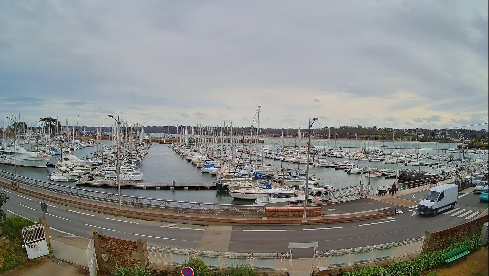 A large marina filled with numerous sailboats and motorboats under an overcast sky.