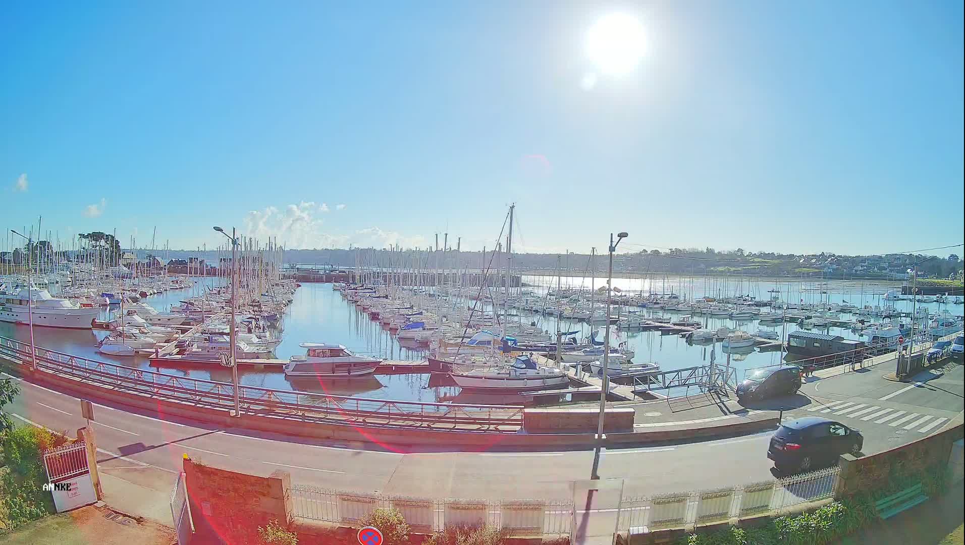 A marina filled with numerous sailboats and motorboats on a sunny day.