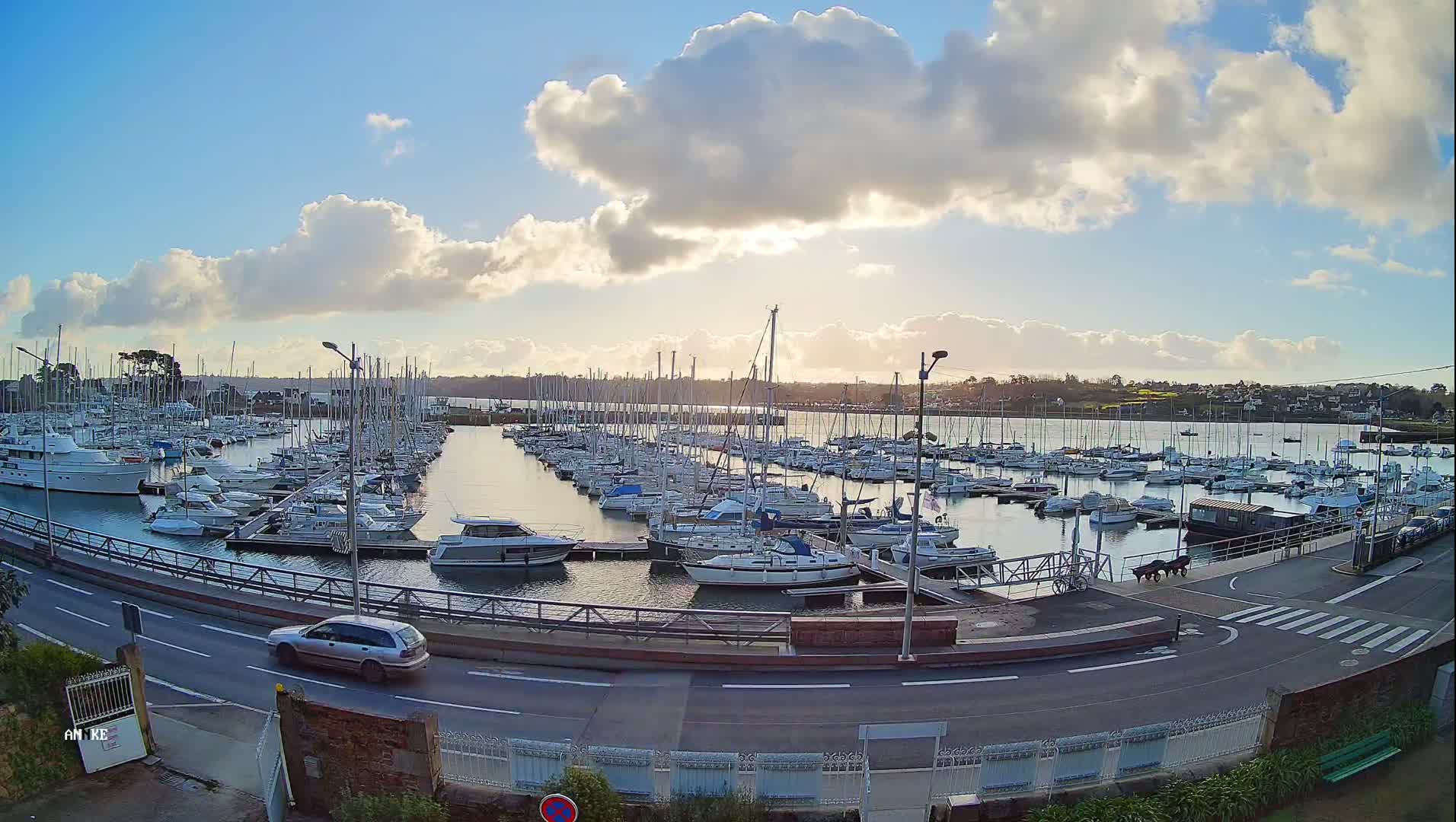 A marina filled with numerous sailboats and motorboats under a partly cloudy sky.