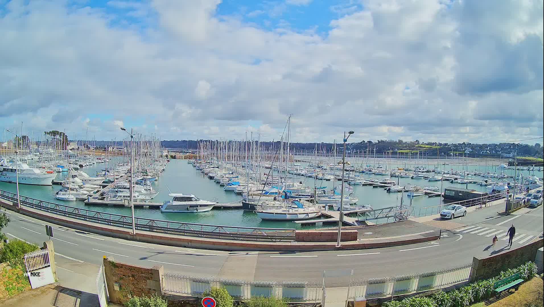 A marina filled with numerous sailboats and motorboats under a partly cloudy sky.