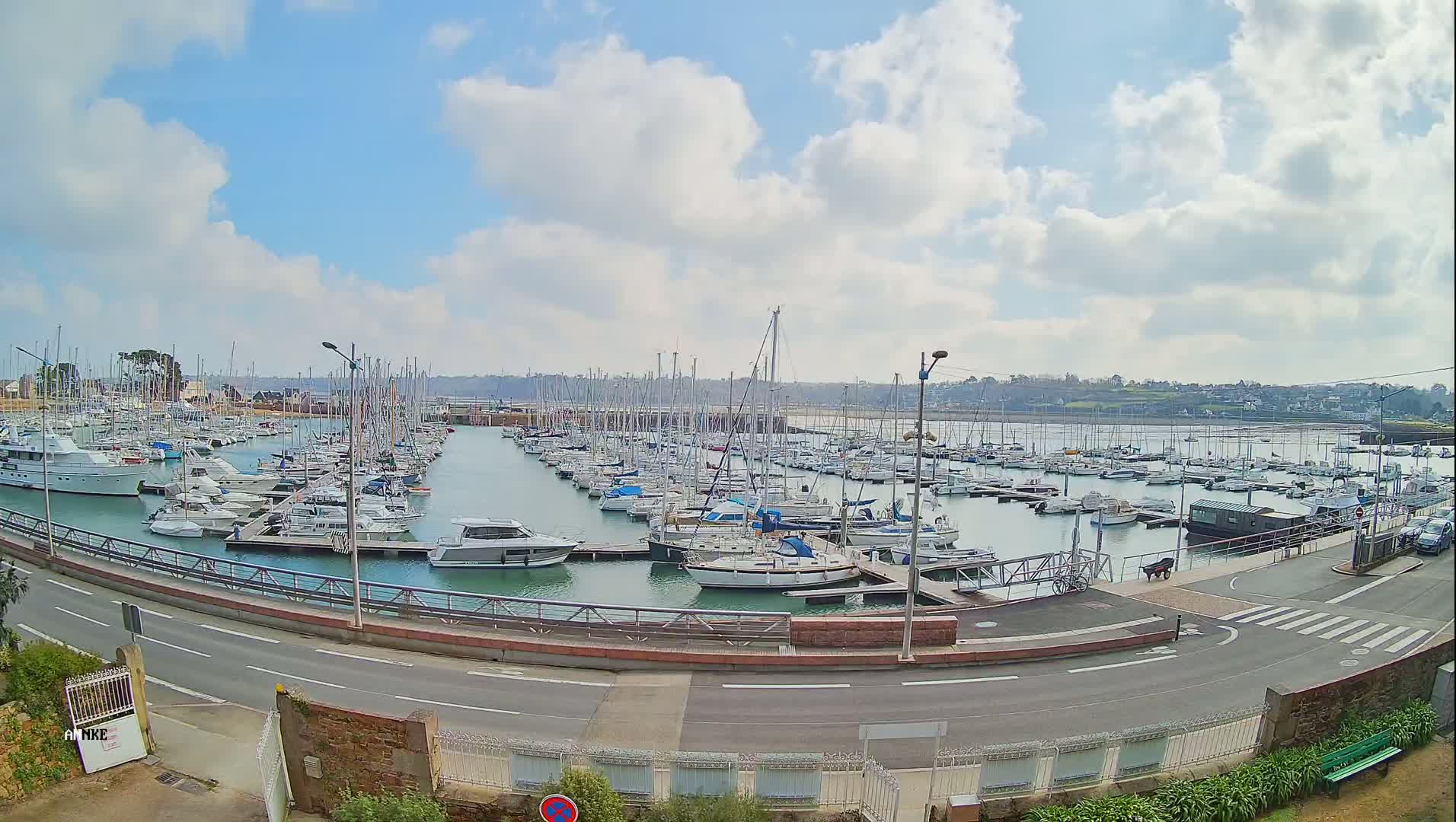 A marina filled with numerous sailboats and motorboats under a partly cloudy sky.
