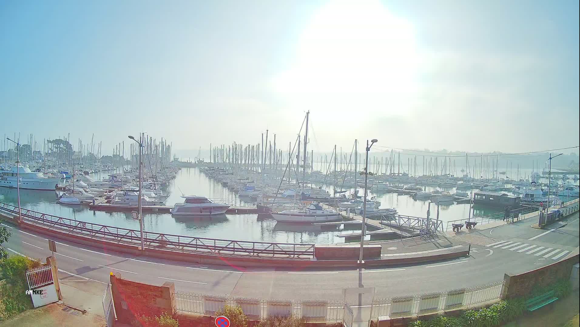 A marina filled with numerous sailboats and motorboats on a hazy, sunny day.