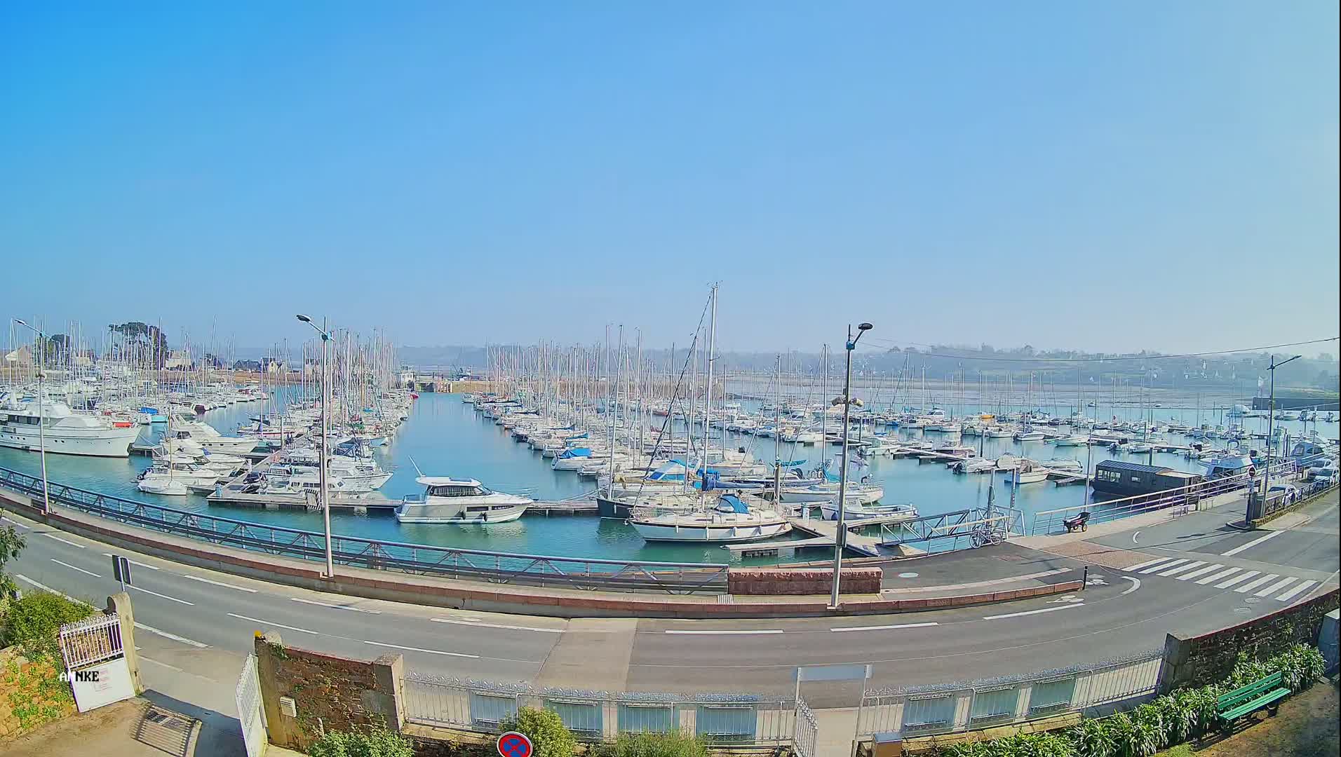 A marina filled with numerous sailboats and motorboats under a clear blue sky.