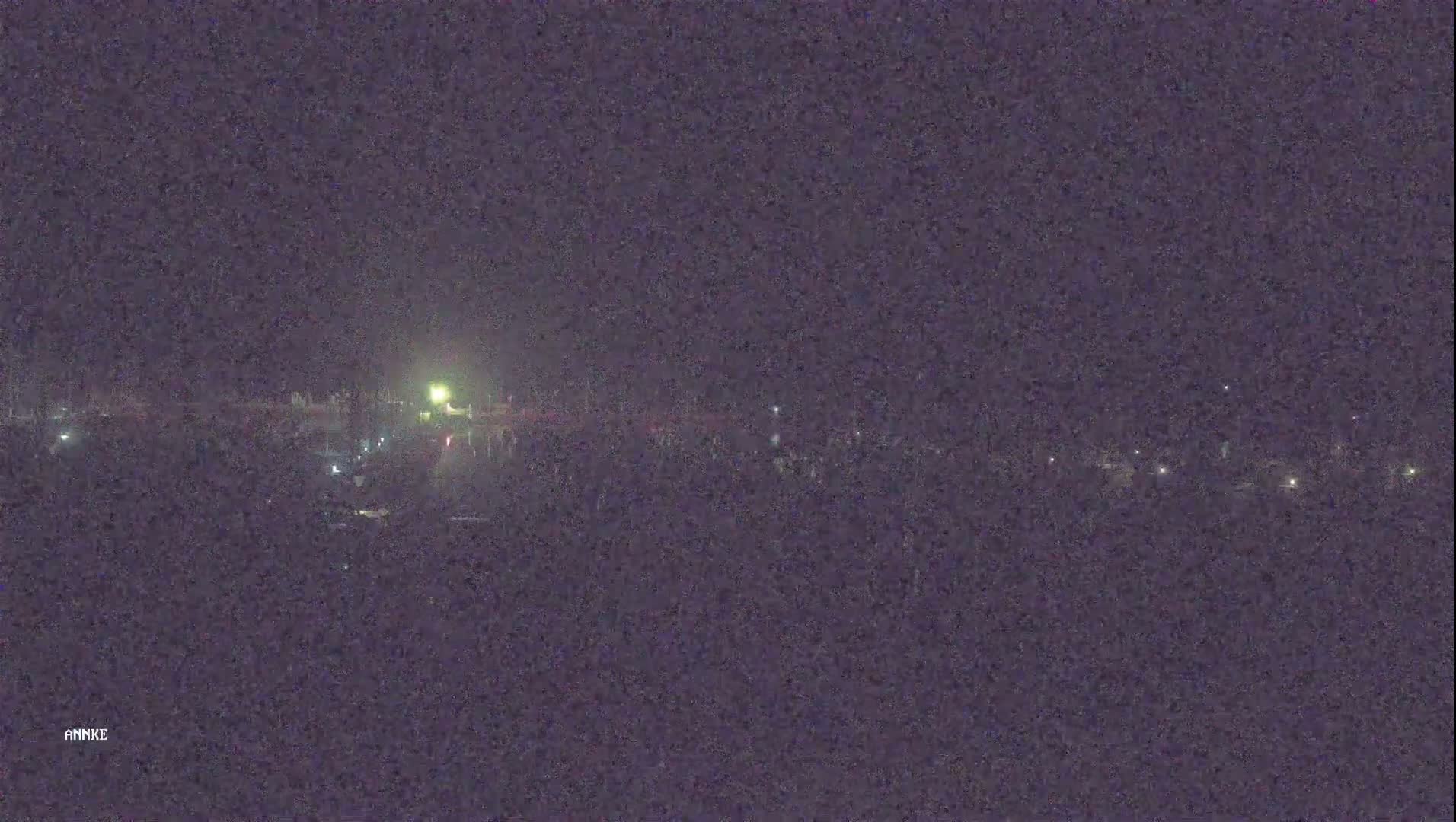 At night, a long, dimly lit road stretches into the distance, with sparse vehicles visible.