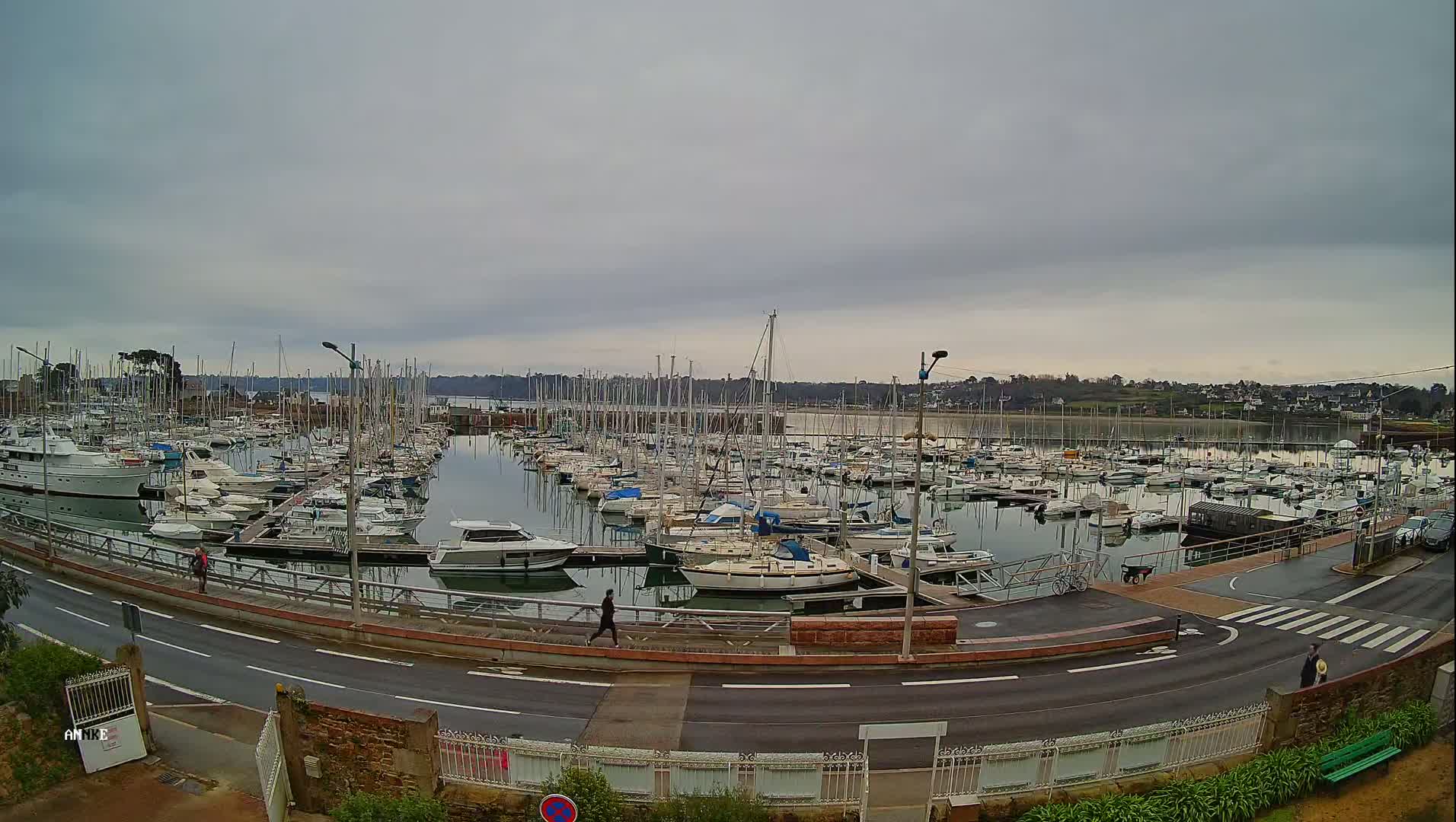 A large marina filled with numerous sailboats and motorboats is situated under an overcast sky.