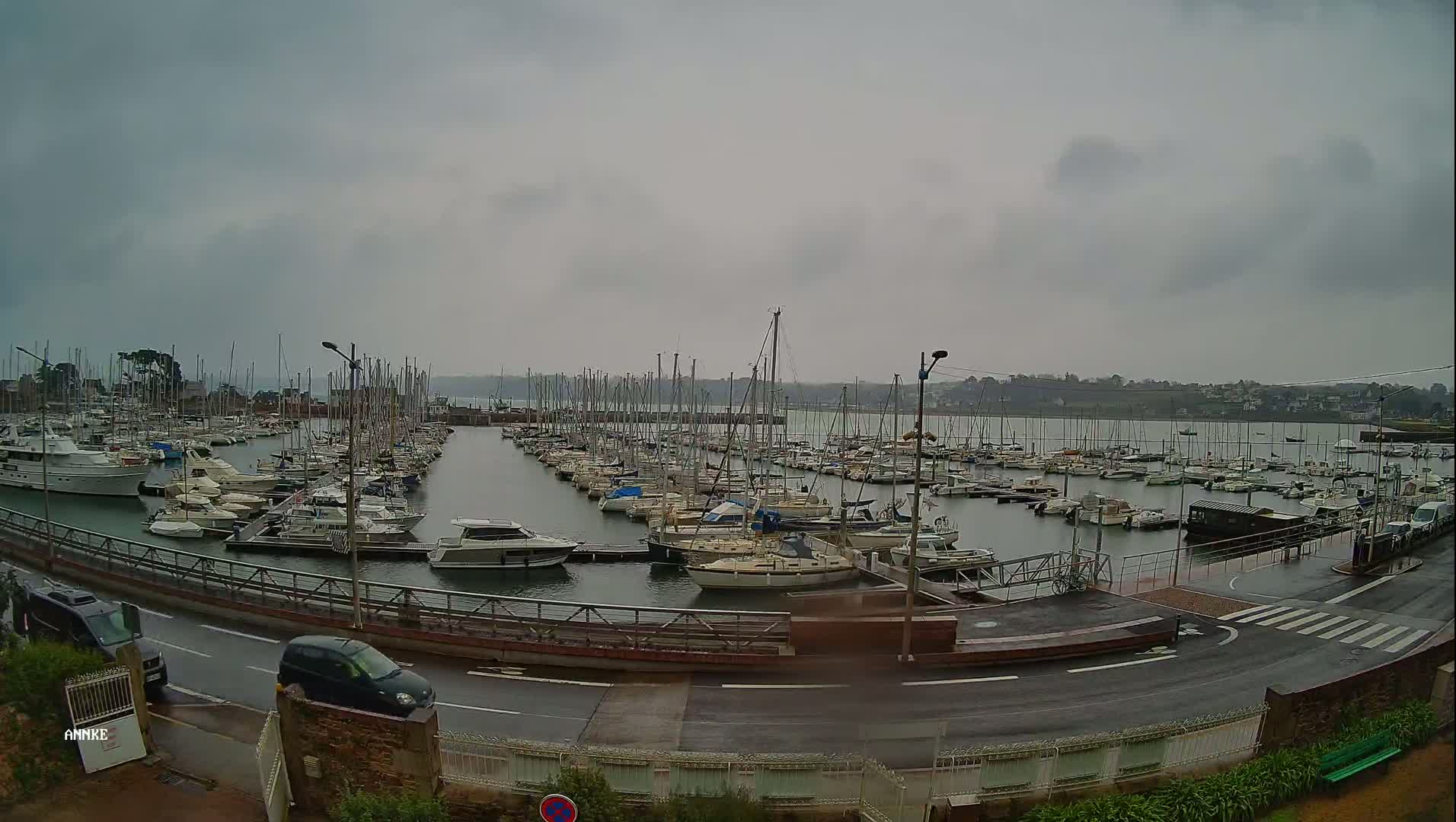 A marina filled with numerous sailboats and motorboats is seen on an overcast day.