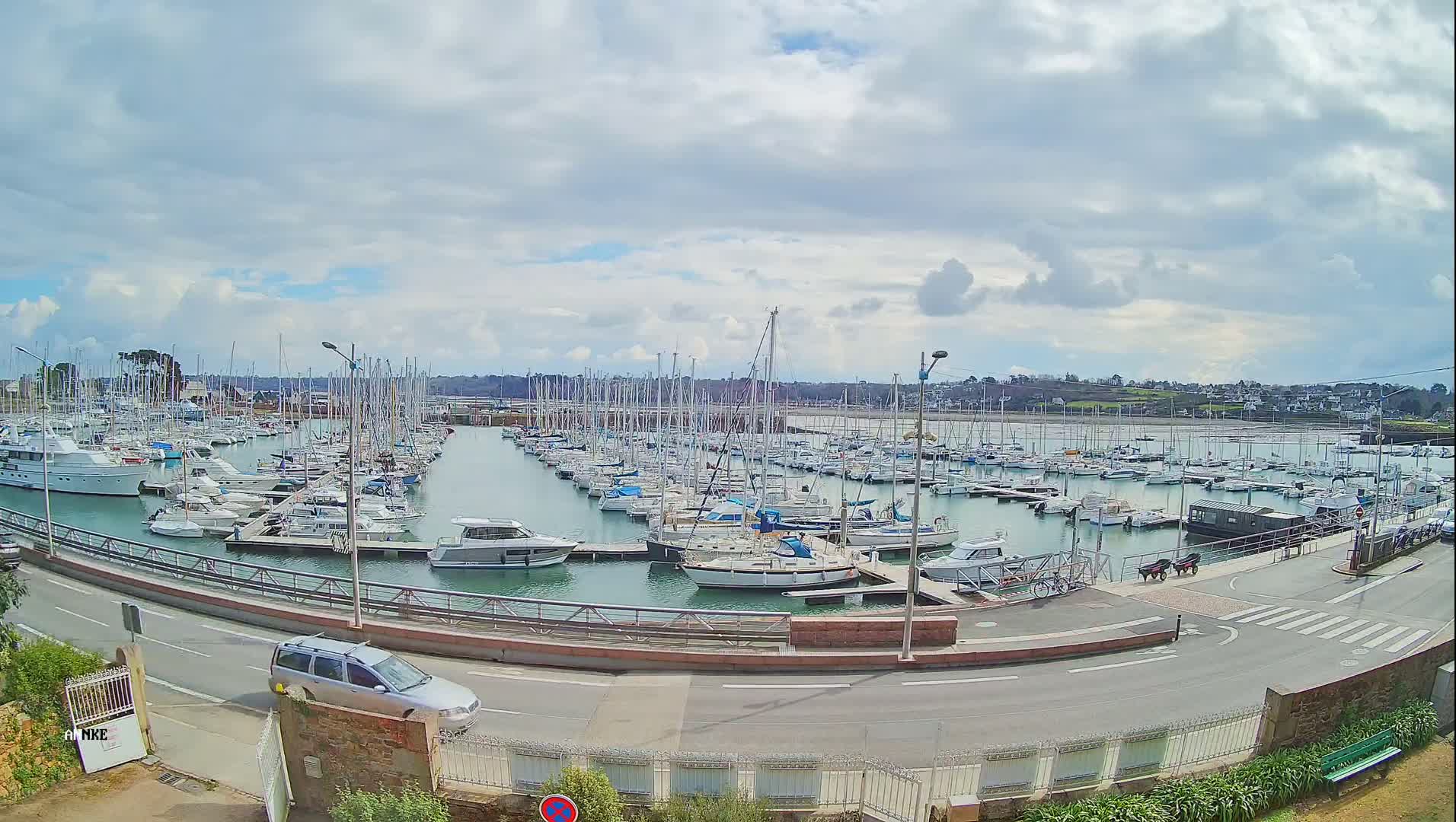 A marina filled with numerous sailboats and motorboats under a partly cloudy sky.