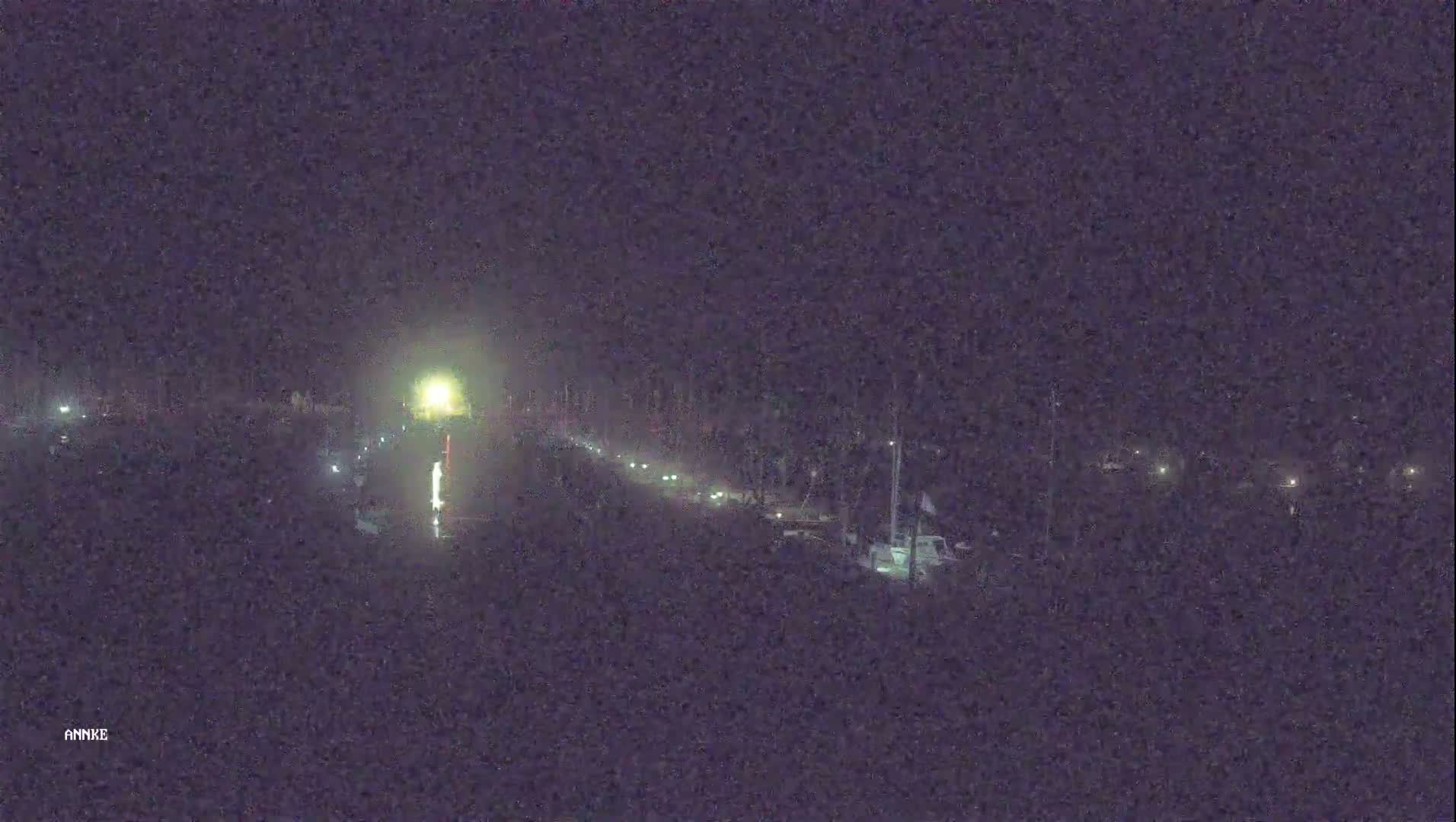 A nighttime view of a road with several vehicles traveling in both directions, illuminated by streetlights and vehicle headlights.