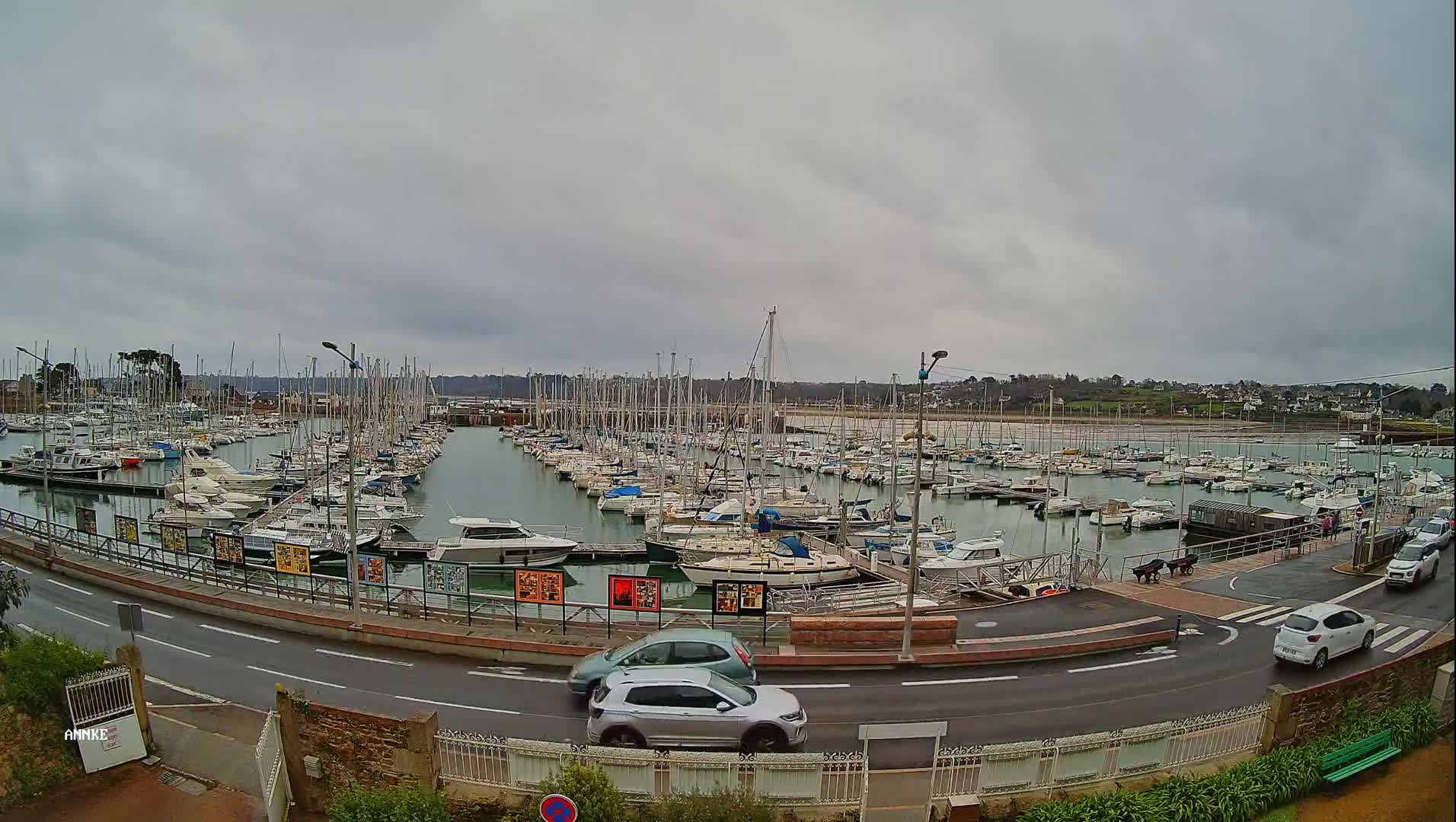 A large marina filled with numerous sailboats and motorboats under a cloudy sky.