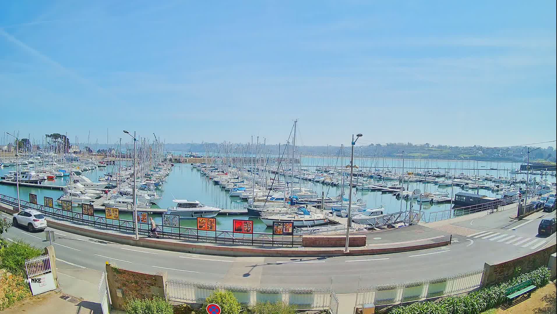 A large marina filled with numerous sailboats and motorboats is seen on a sunny day.
