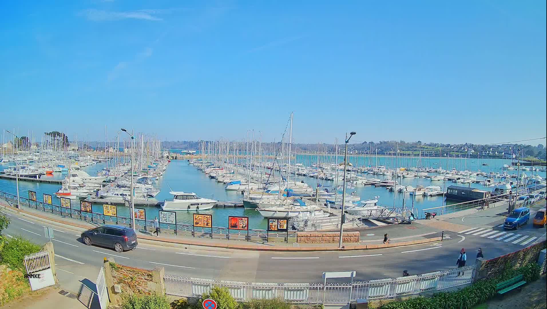 A marina filled with numerous sailboats and motorboats under a clear blue sky on a sunny day.