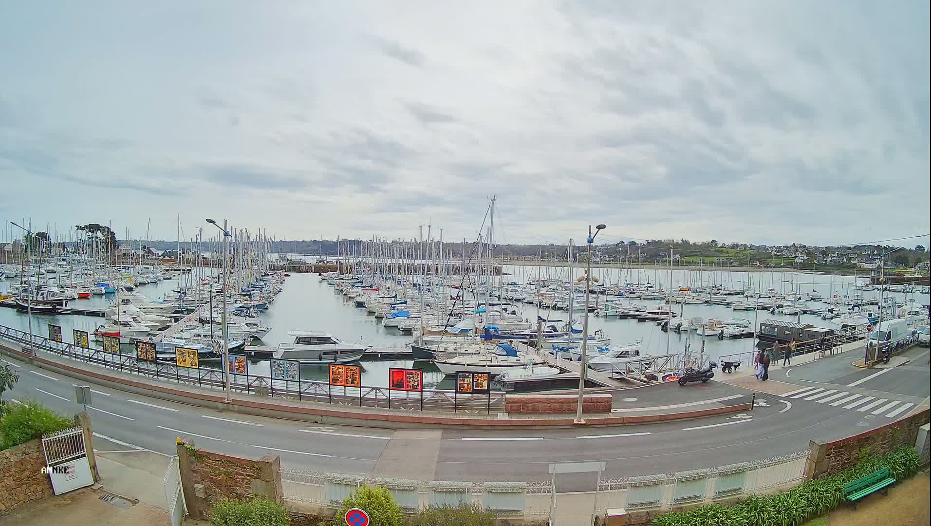 A large marina filled with numerous sailboats and motorboats is shown under a cloudy sky.