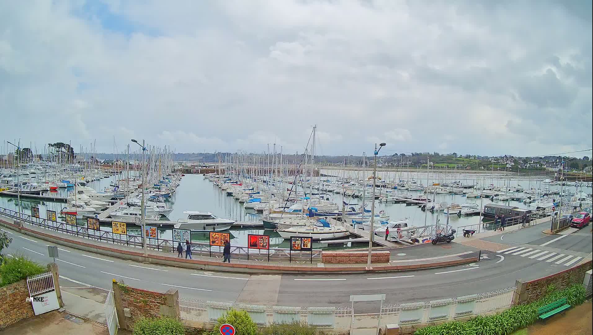 A large marina filled with numerous sailboats and motorboats is seen under a cloudy sky.