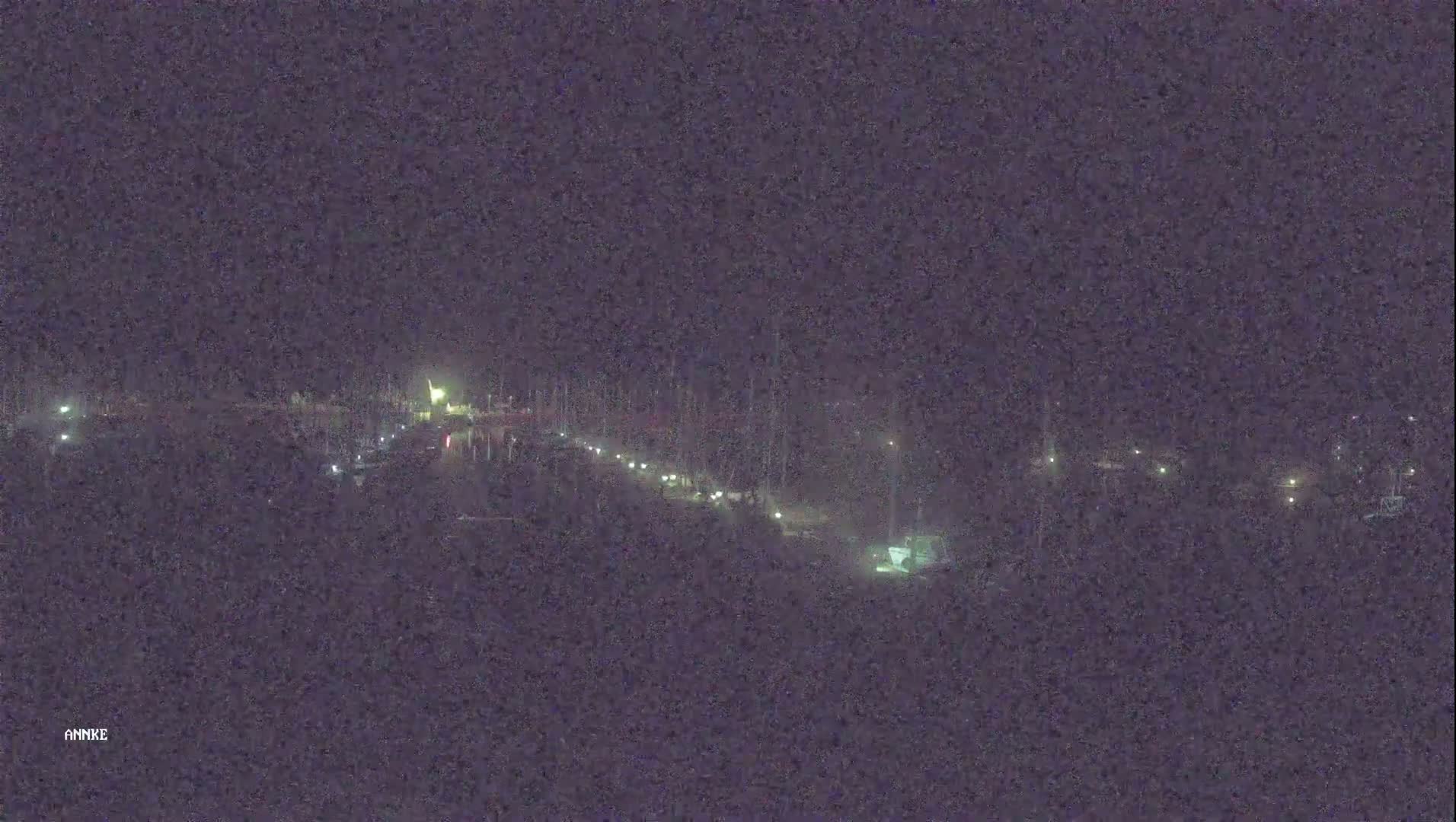 A long, dark road at night with sparsely spaced lights visible along its length.