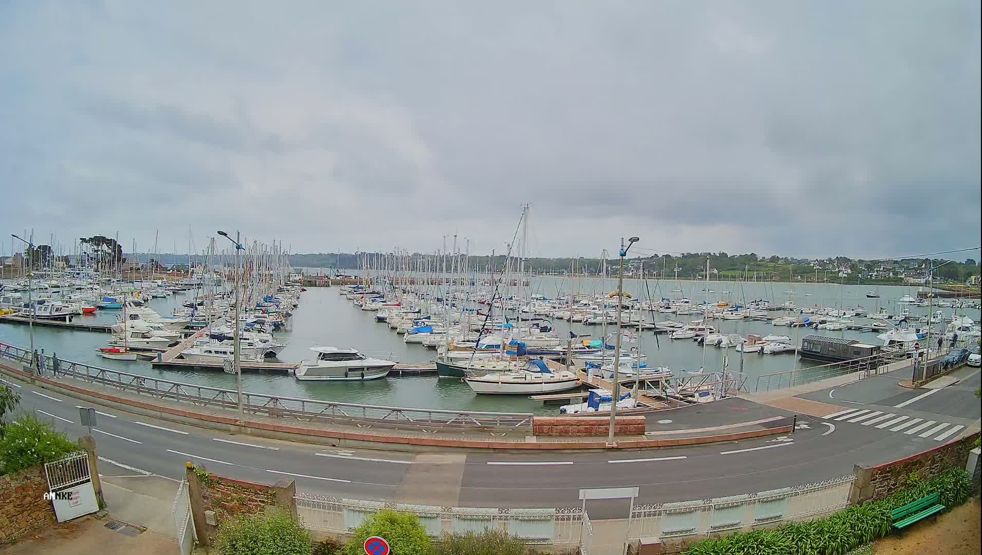 A large marina filled with numerous sailboats and motorboats is seen on an overcast day.