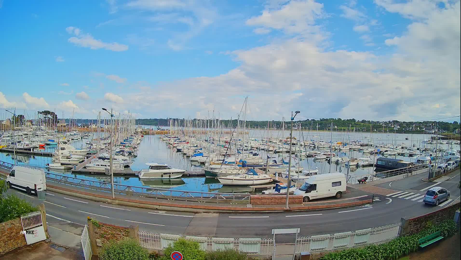 A marina filled with numerous sailboats and motorboats under a partly cloudy sky.